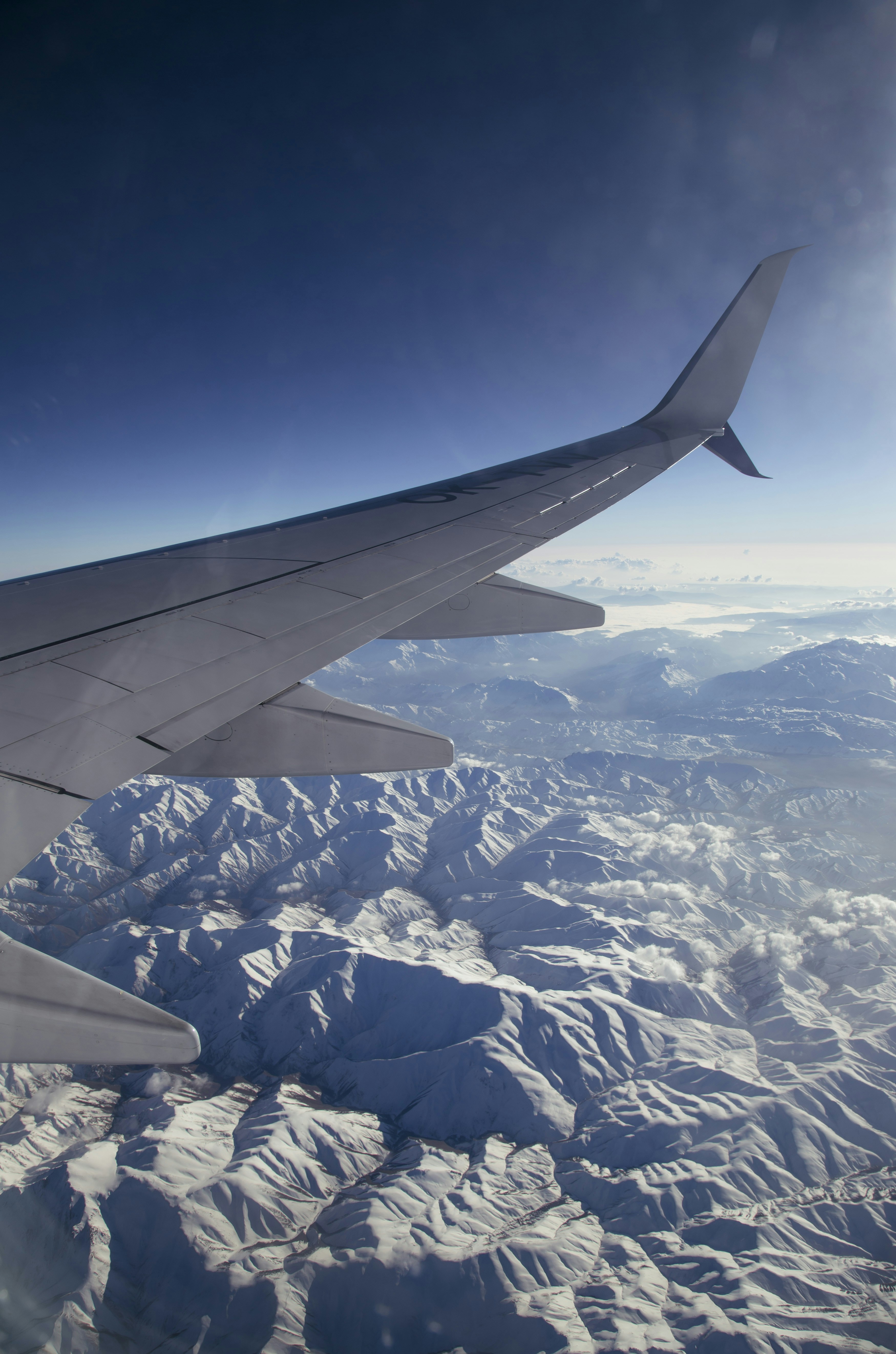 Airplane Wing Over Snow-Covered Mountains