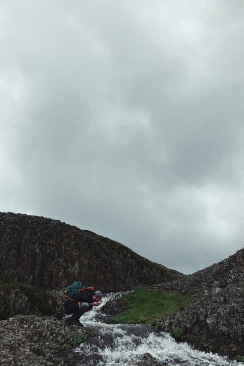 Hiker Drinking From Mountain Stream