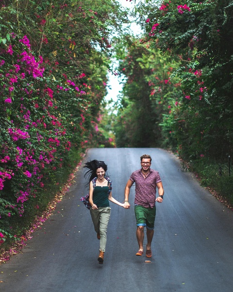 Couple Running Hand in Hand on Flowering Road