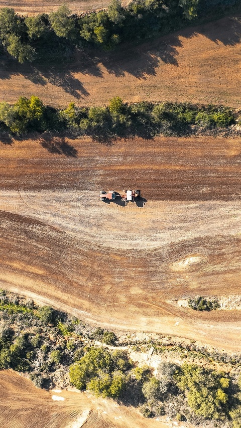Aerial View of Farming Tractors on Plowed Field