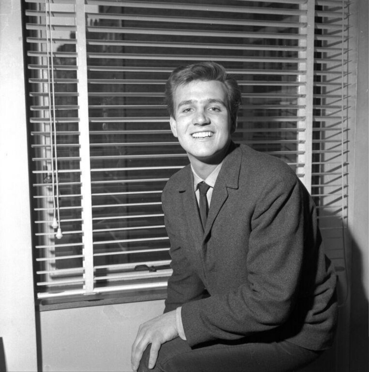 Smiling Young Man by Window Blinds