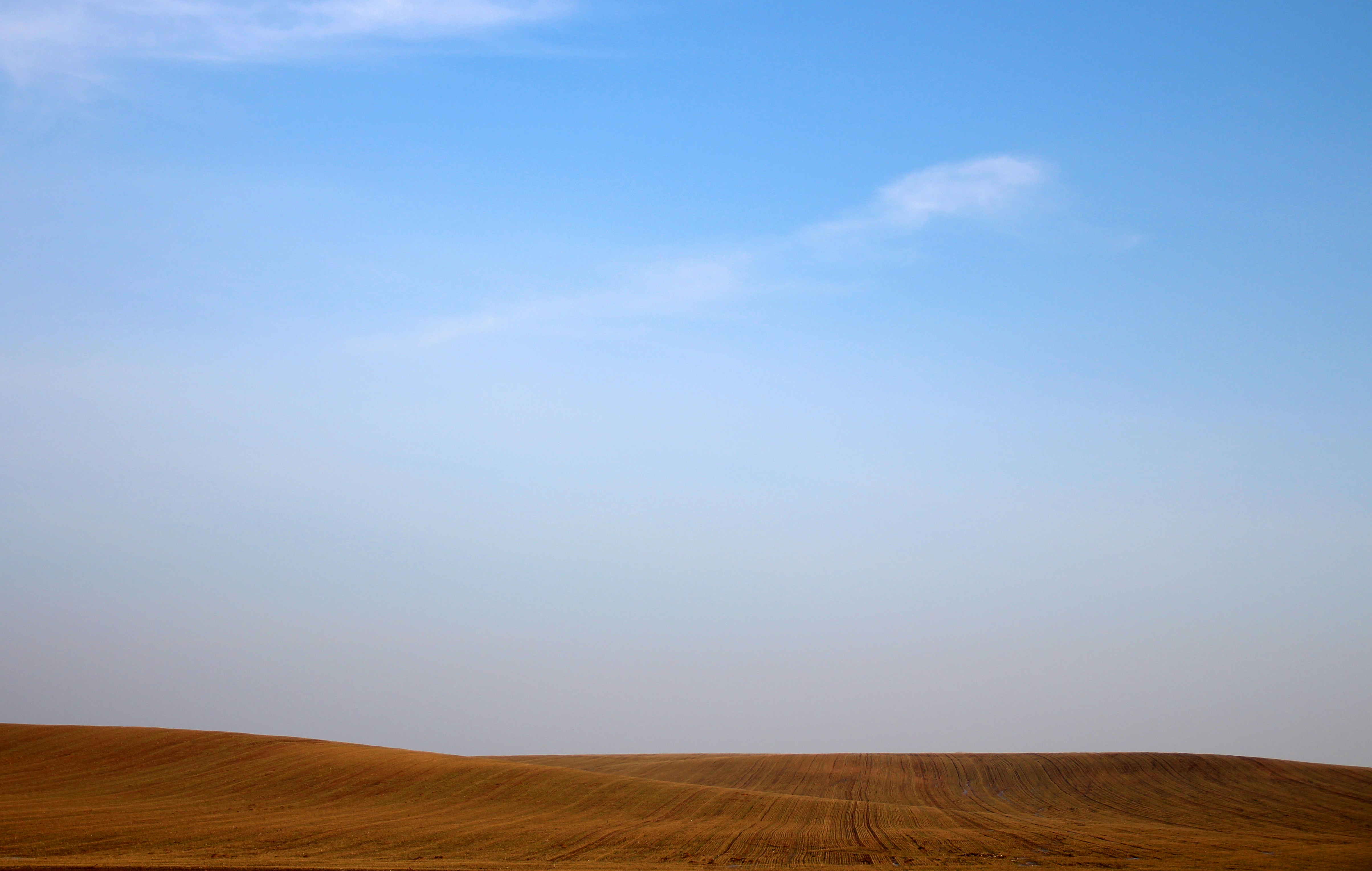 Rolling Plowed Fields Under Blue Sky