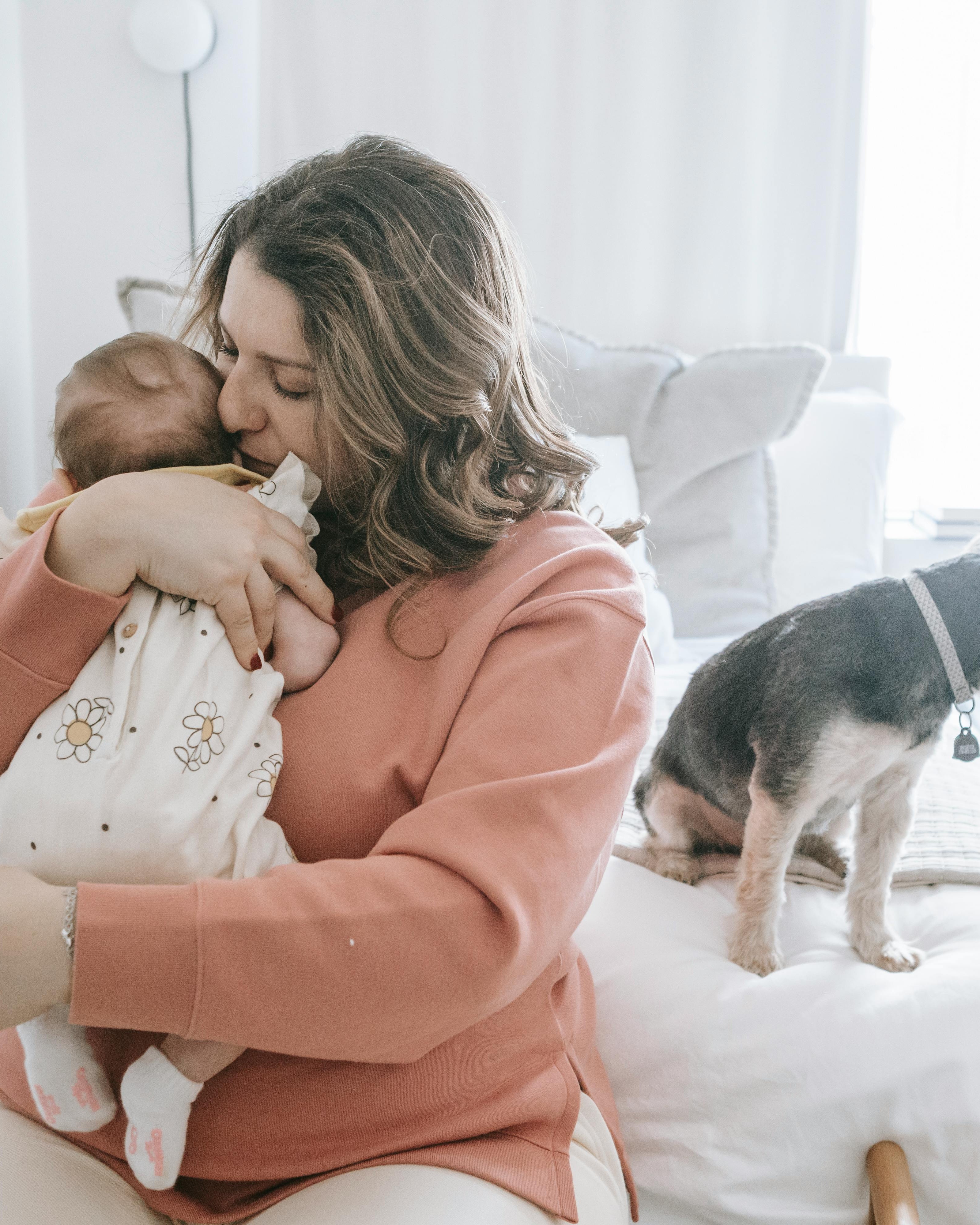 Mother Cuddling Newborn Baby With Pet Dog