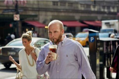Man Drinking While Walking on City Street