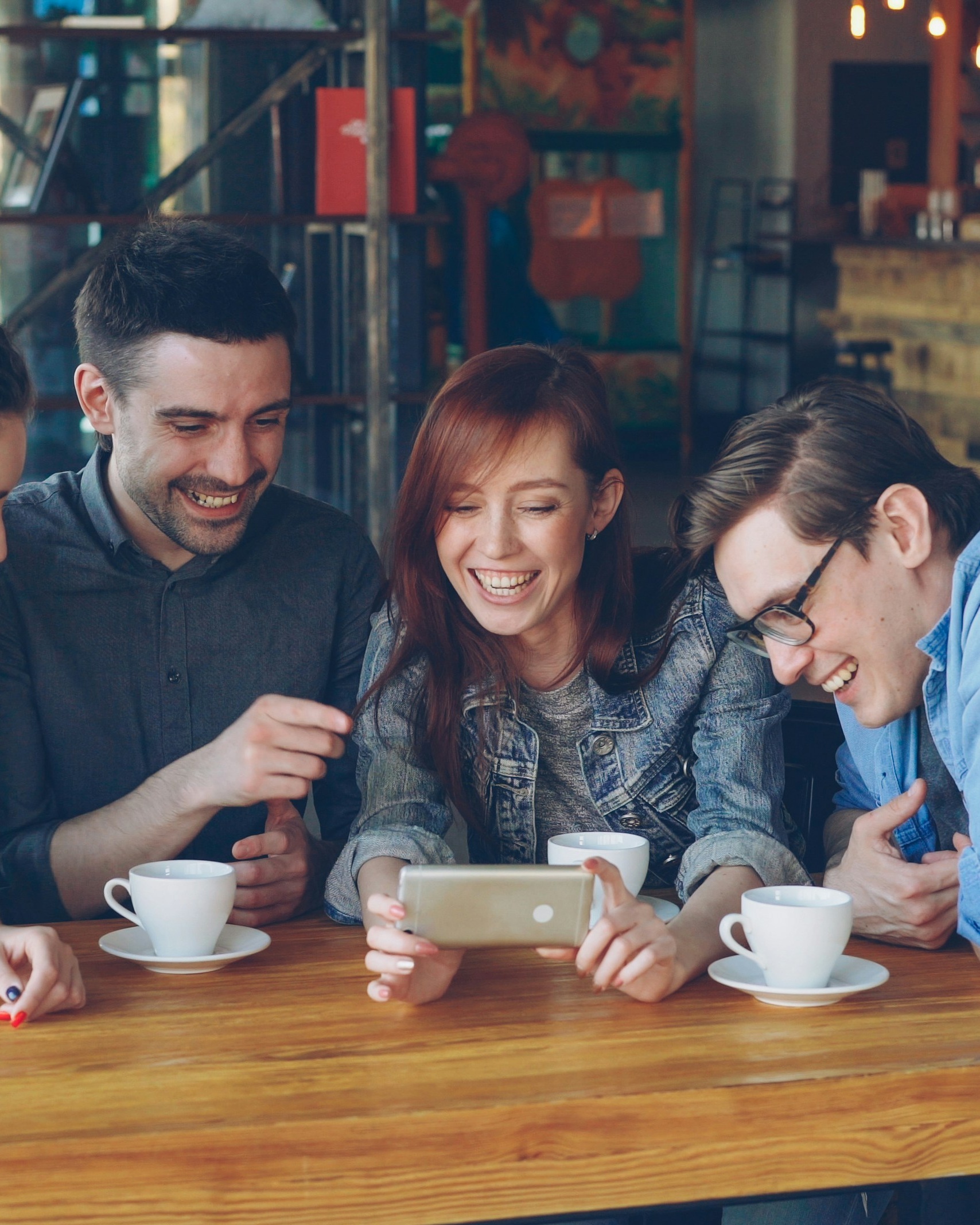 Friends Laughing at Phone in Cafe