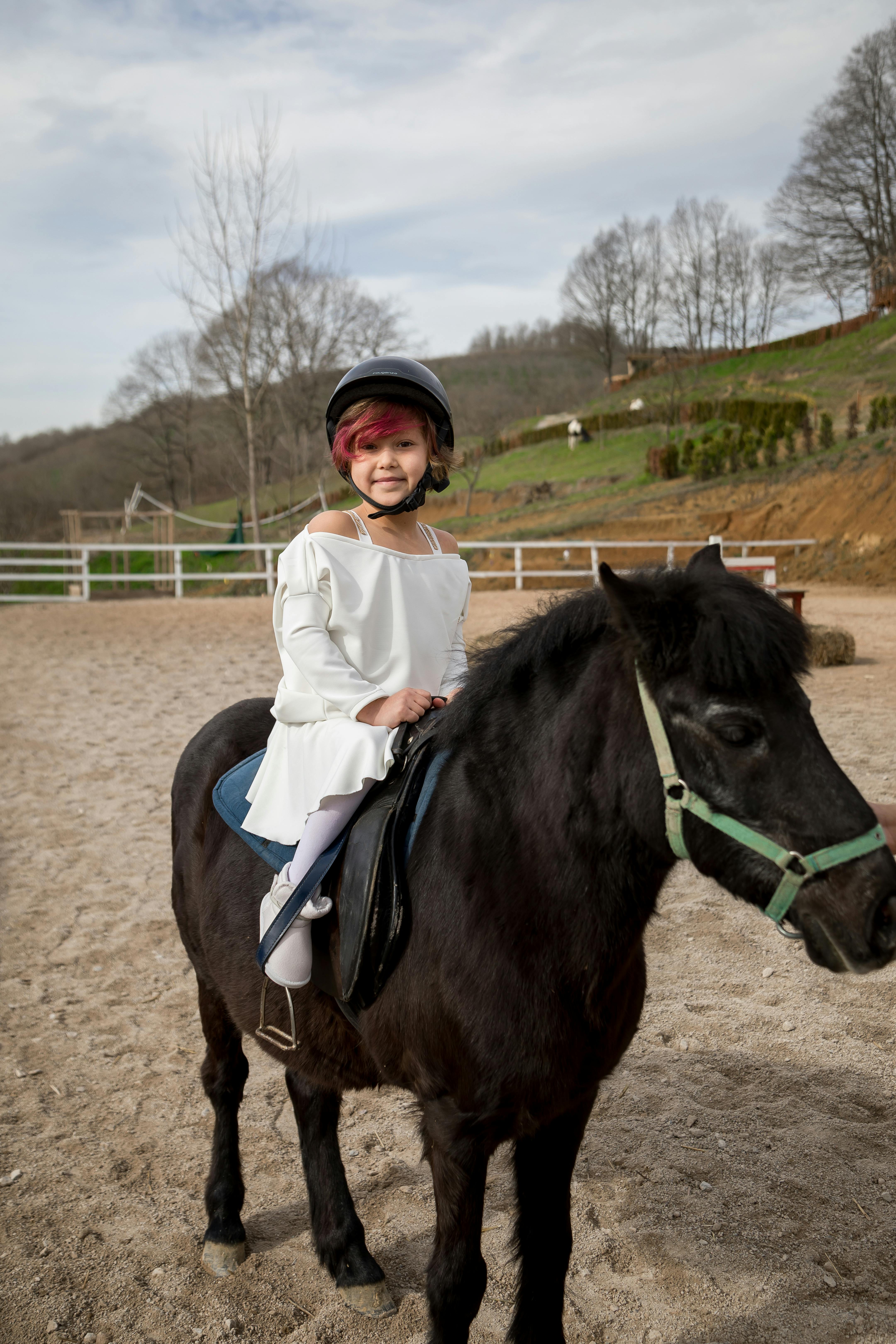 Young Girl Riding Black Pony in Arena
