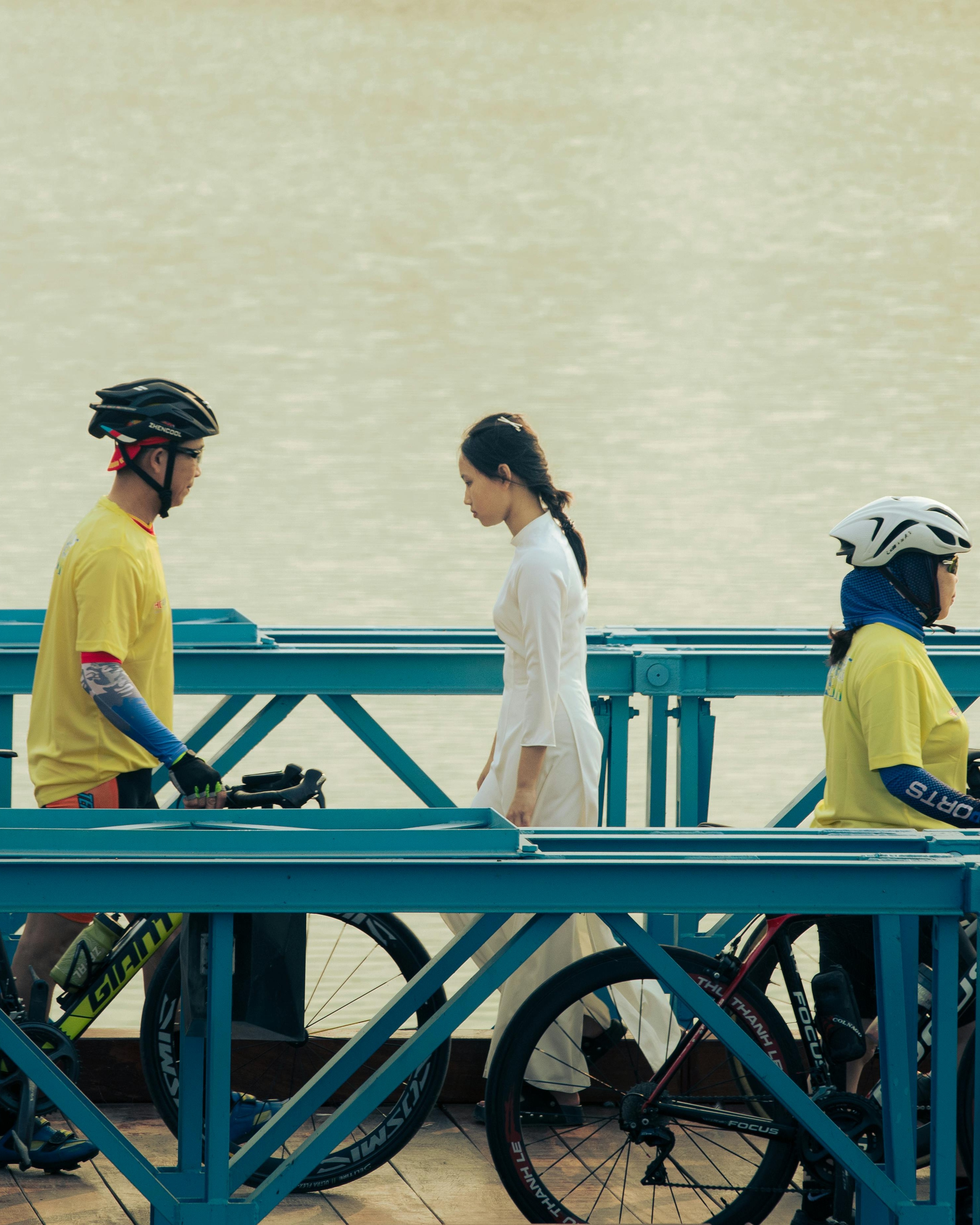 Cyclists and Woman on River Bridge