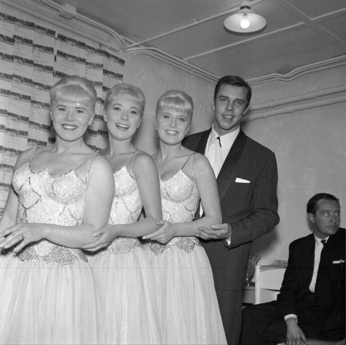 Three singing sisters and a man posing backstage
