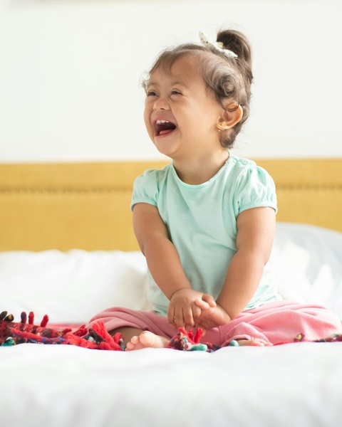 Laughing Toddler Girl on Bed