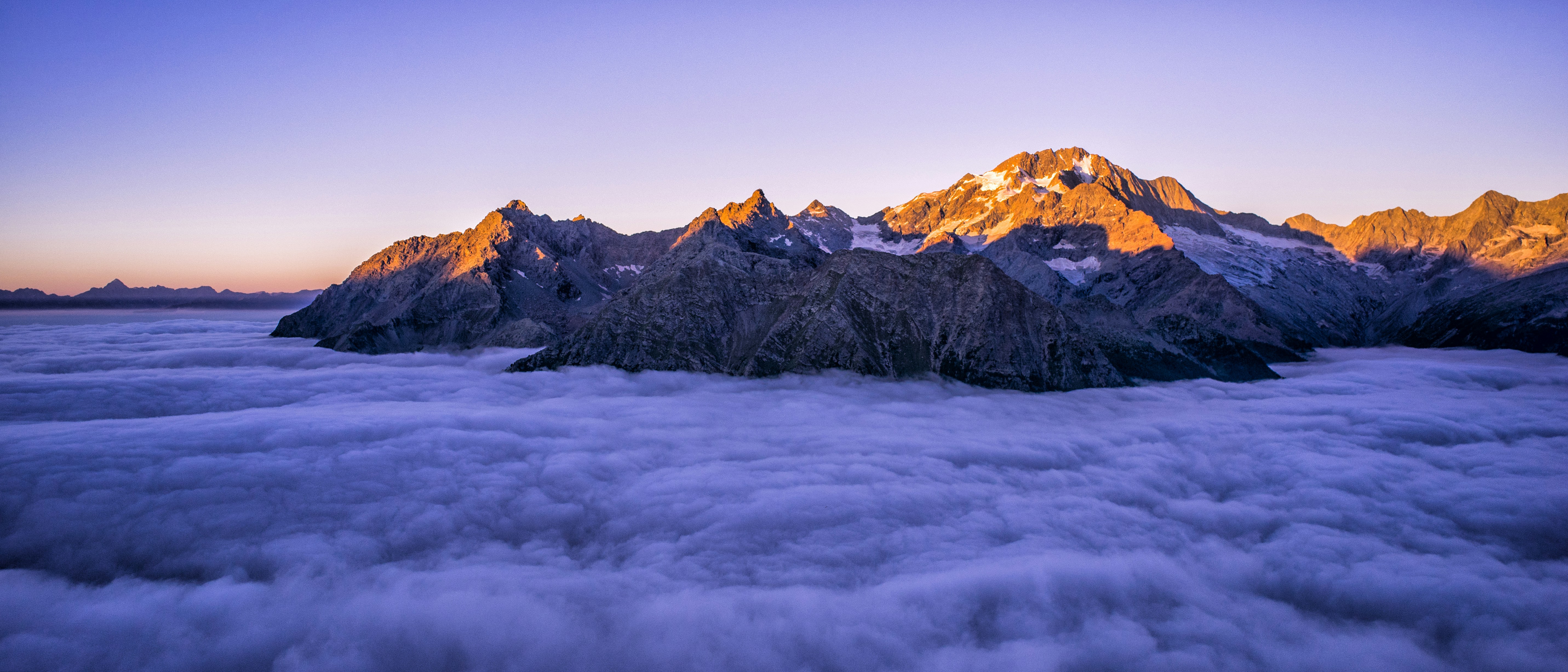 Sunlit Mountain Peaks Above Cloud Sea