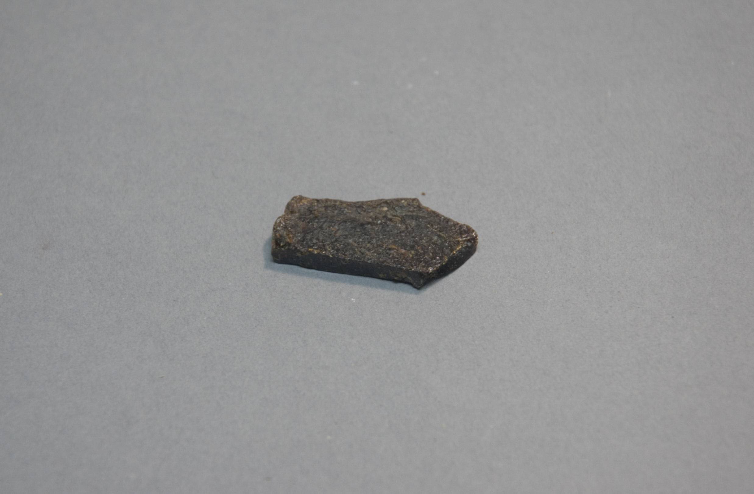 Small Dark Stone Fragment on Gray Background