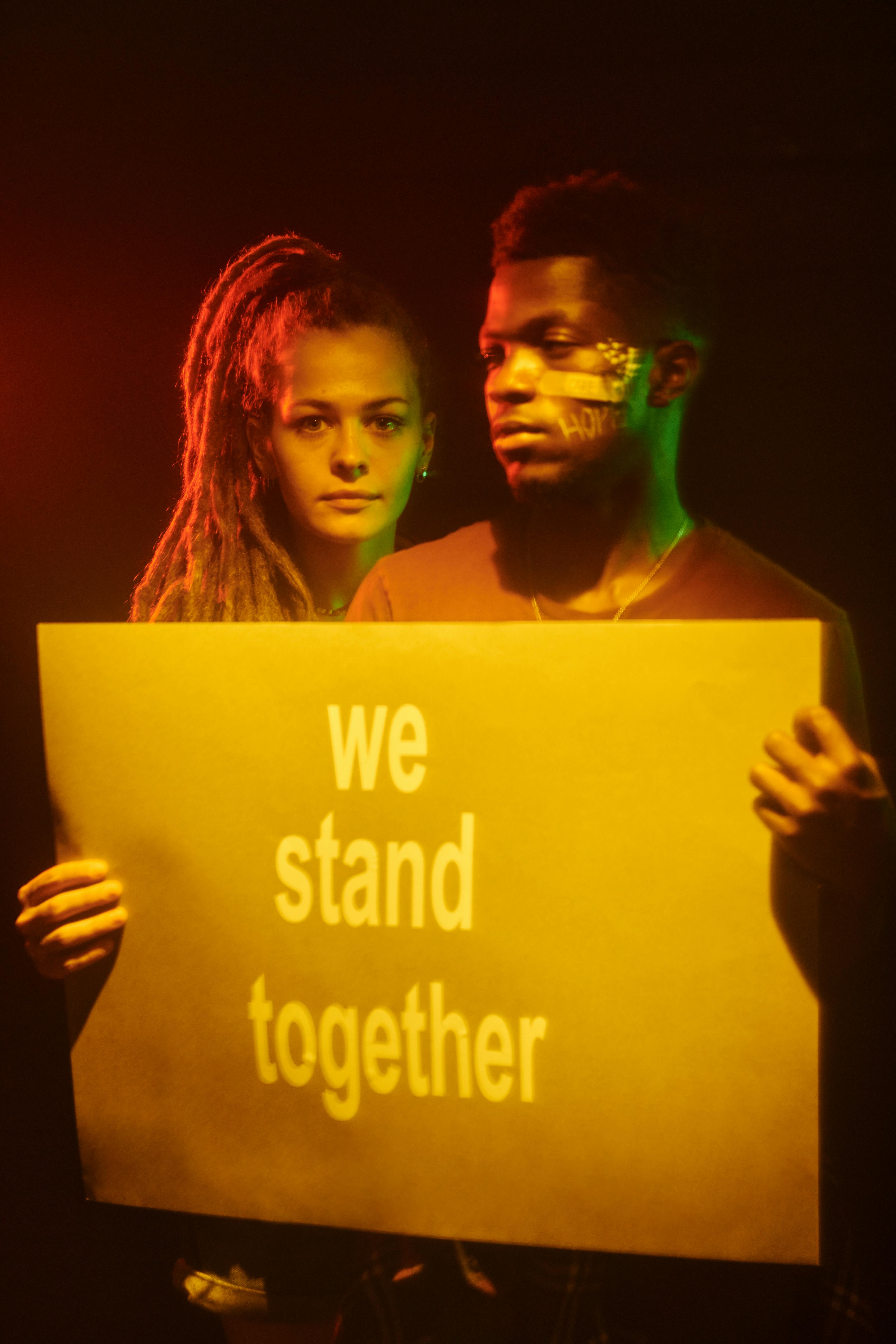 Two People Holding We Stand Together Sign