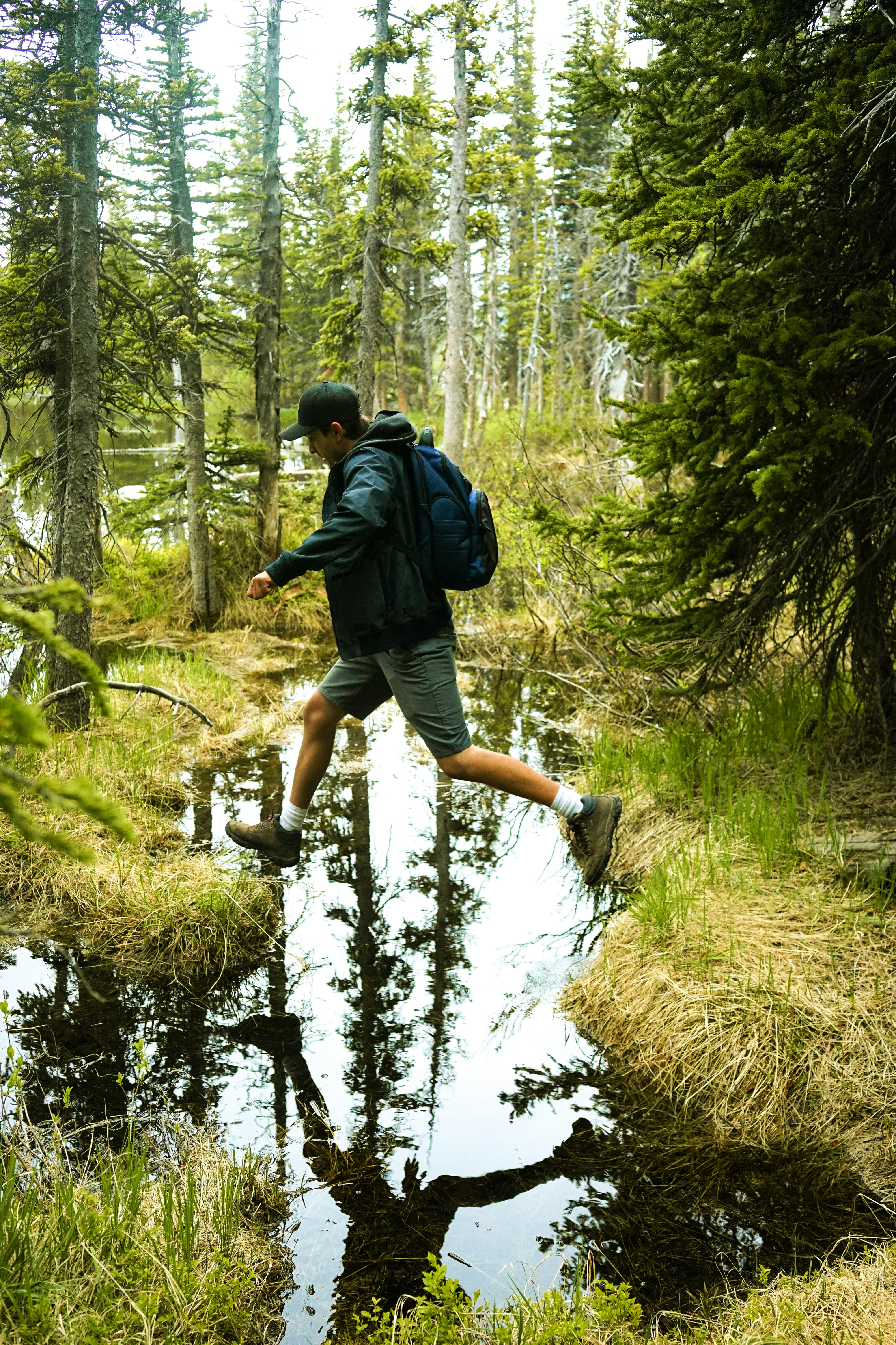Hiker Jumping Stream in Forest