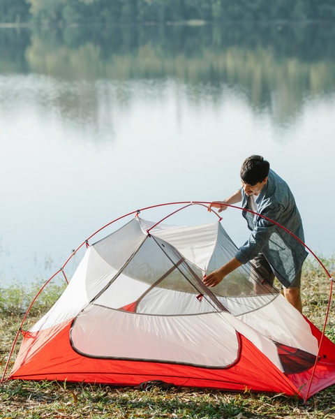Man Setting Up Tent By Lakeside