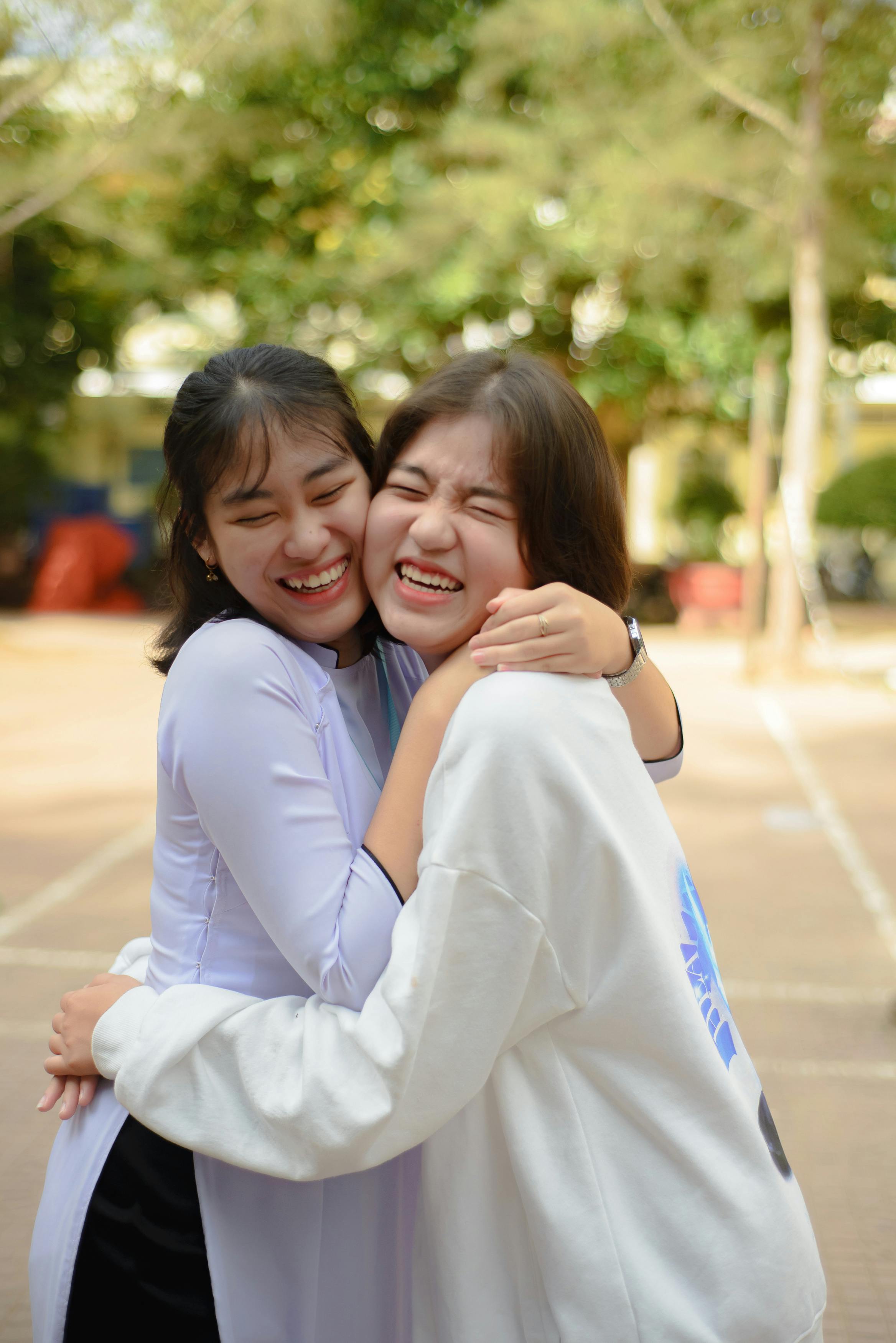 Two Friends Laughing While Hugging Outdoors