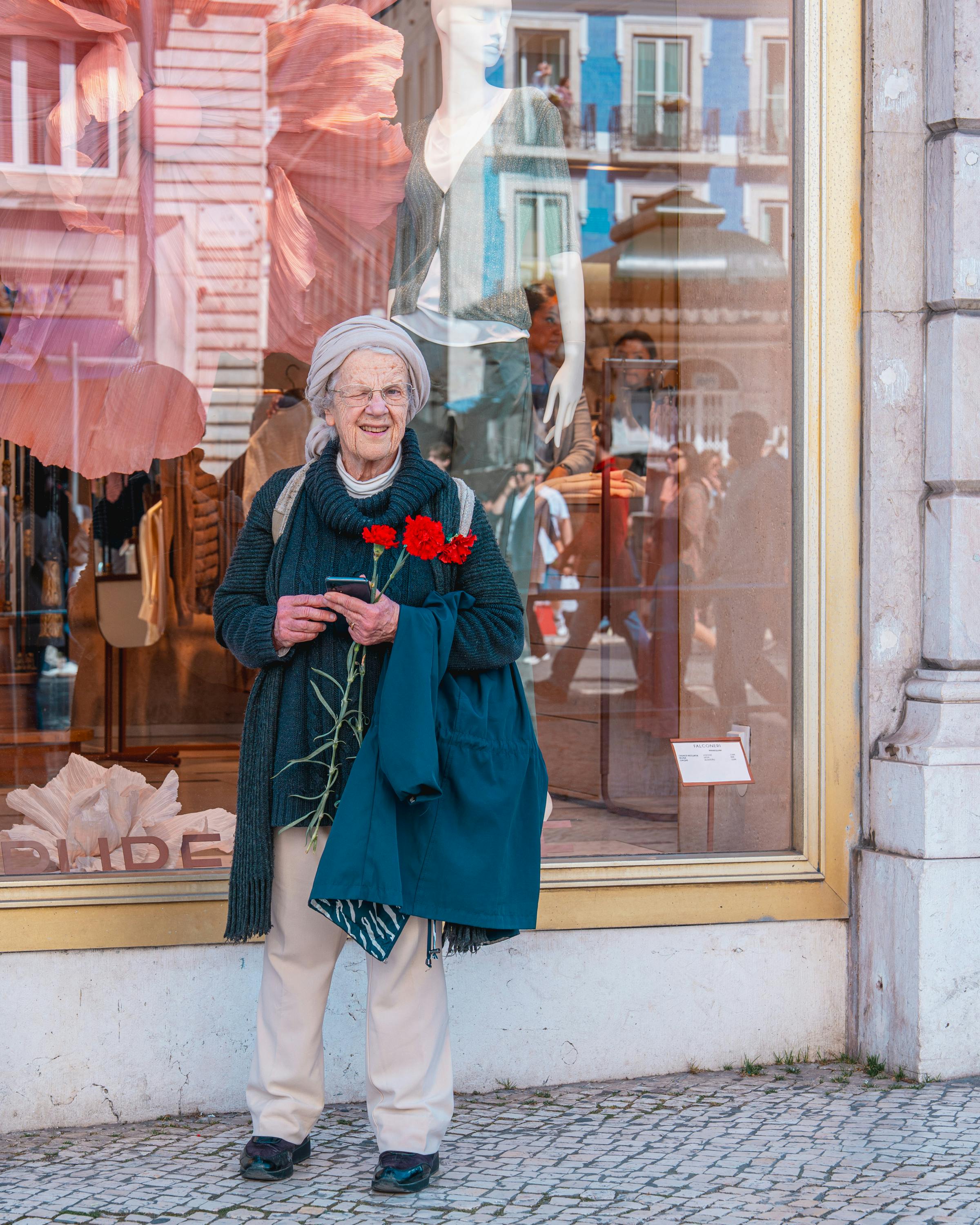 Elderly Woman With Red Carnations Outside Shop