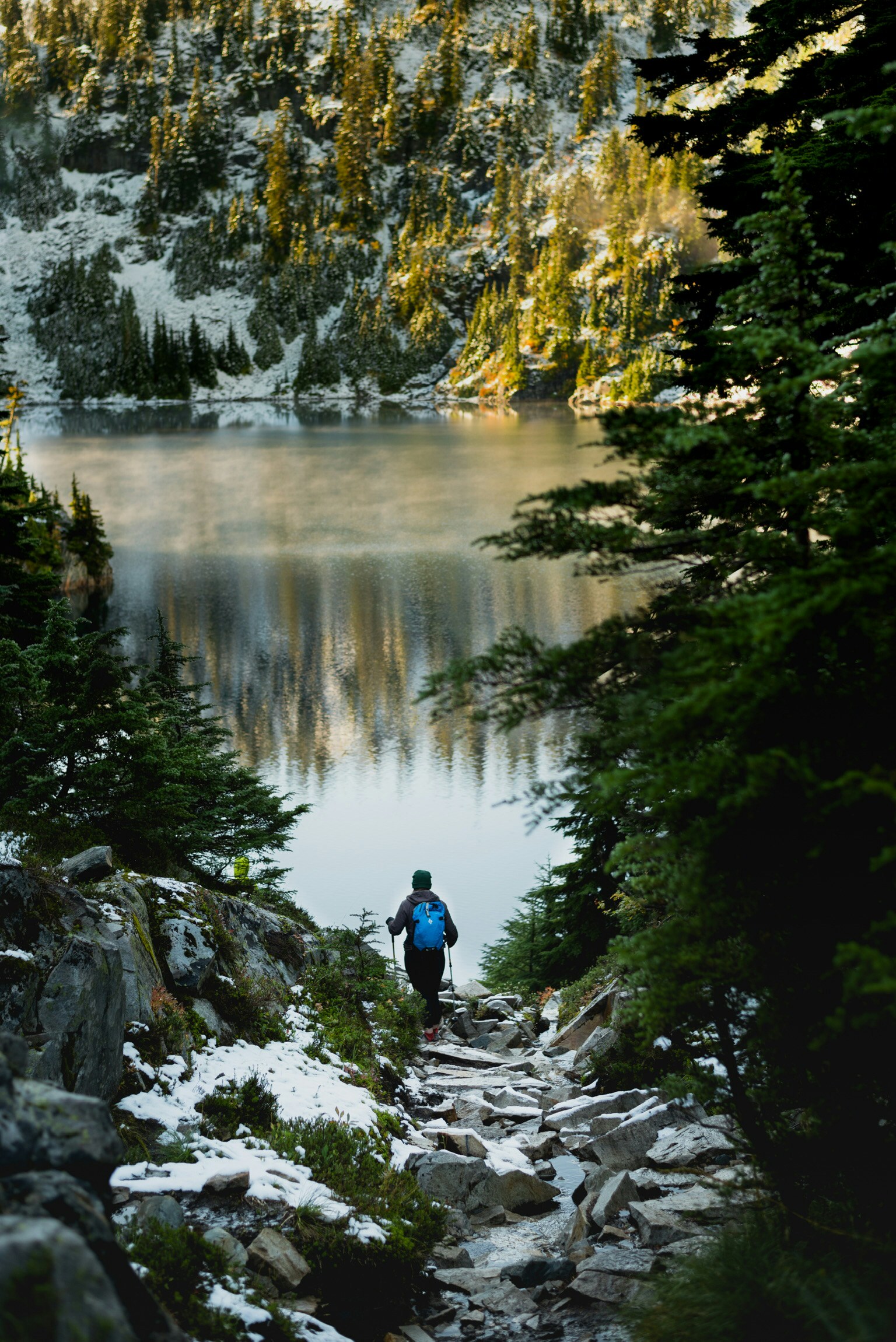 Hiker Approaches Snowy Alpine Lake