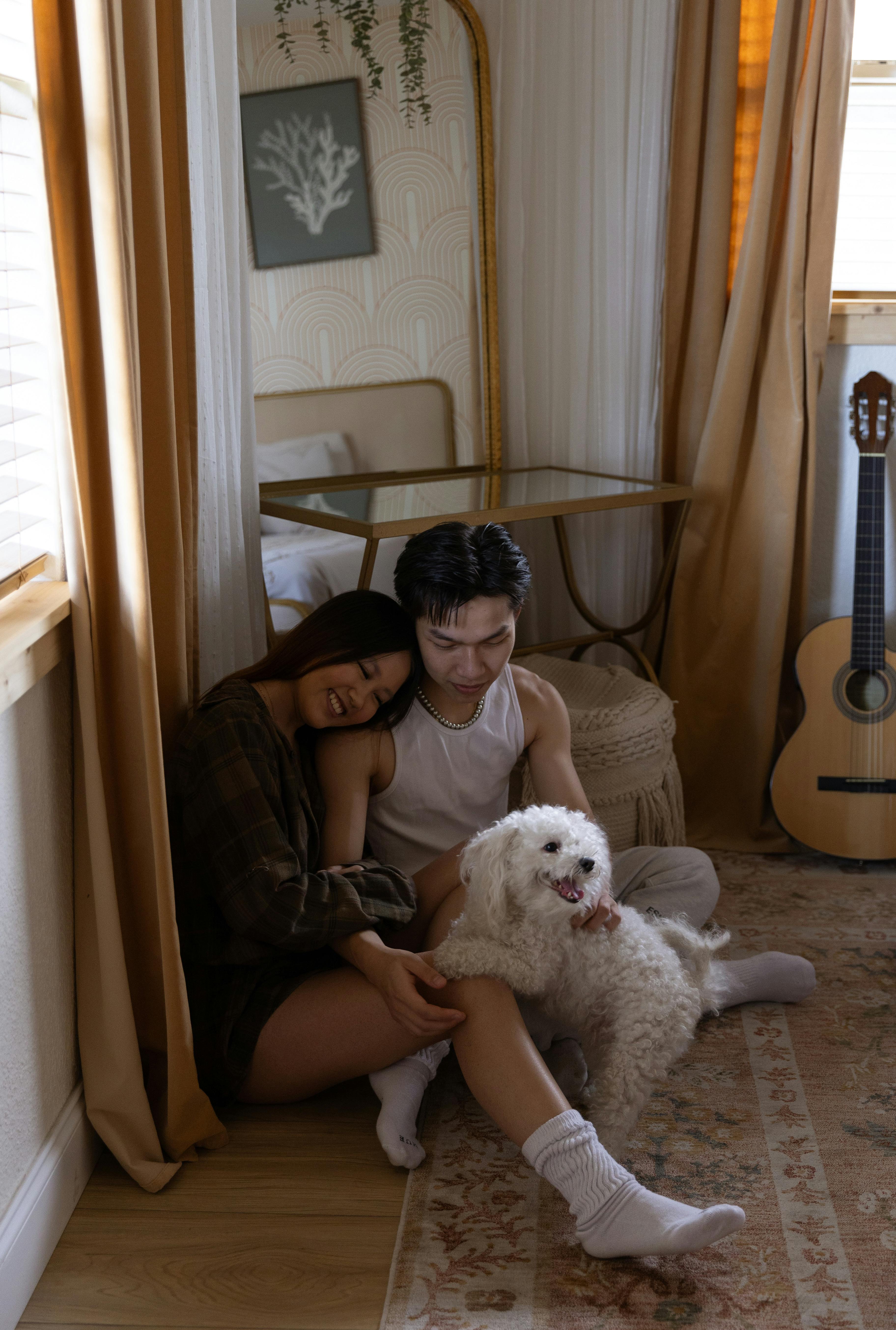 Couple With Dog Relaxing In Cozy Bedroom