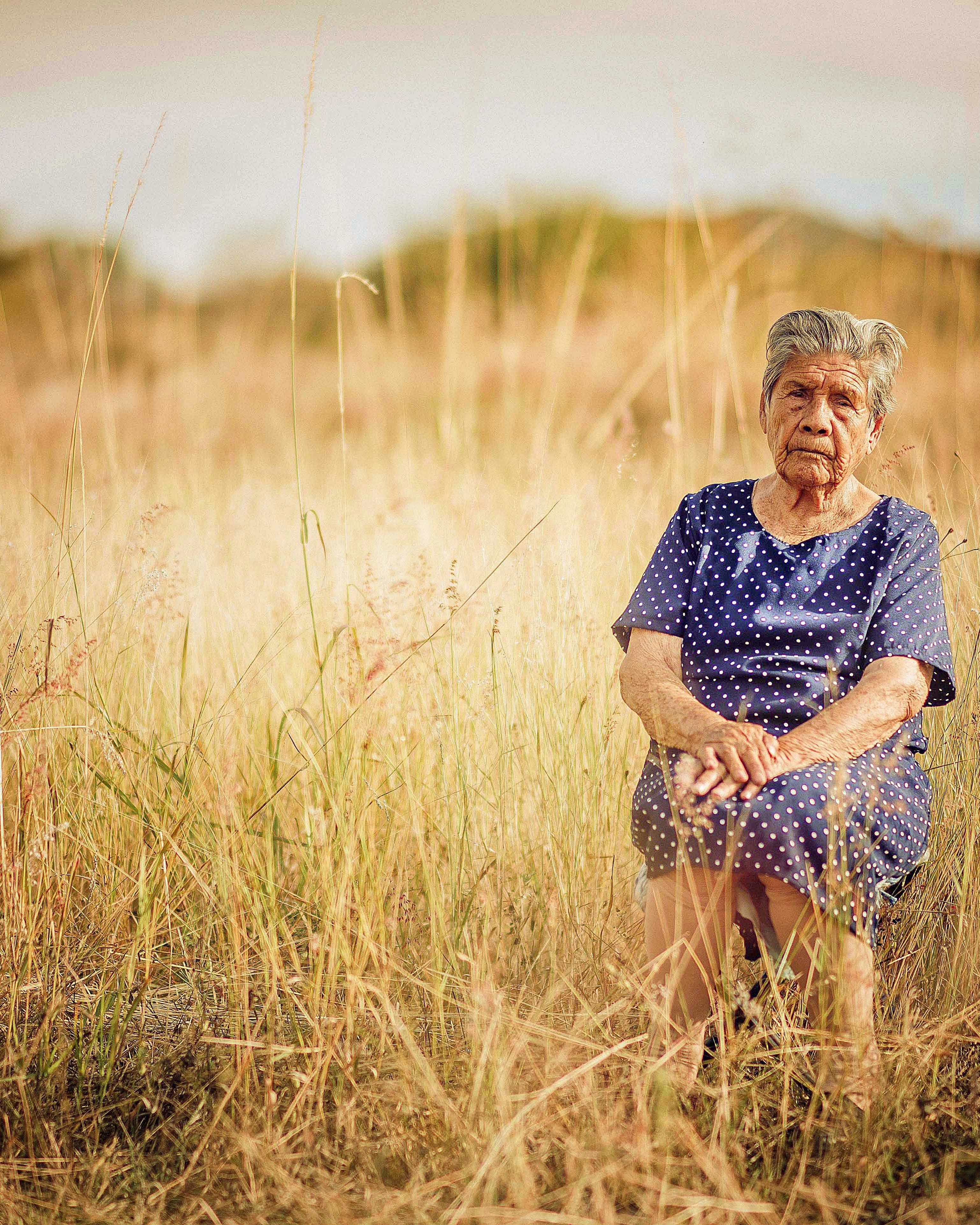 Elderly Woman in Golden Grass Field