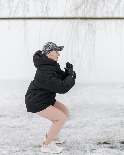 Senior Woman Doing Squats in Snow