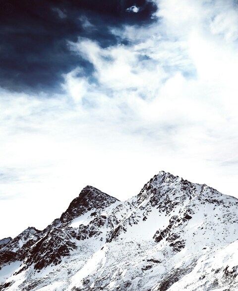 Snow-Capped Mountains Under Cloudy Sky