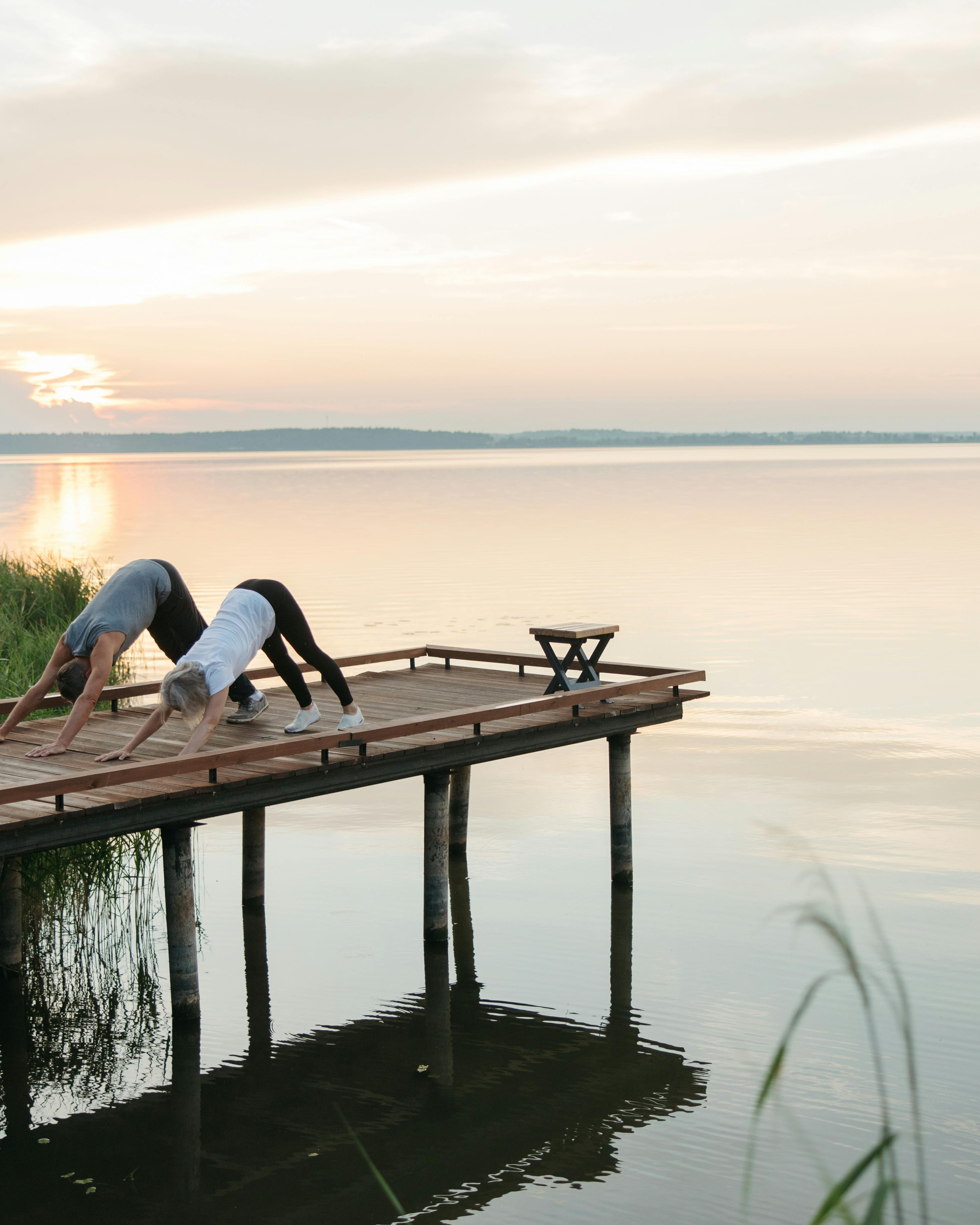 Two People Doing Yoga by Lake at Sunset