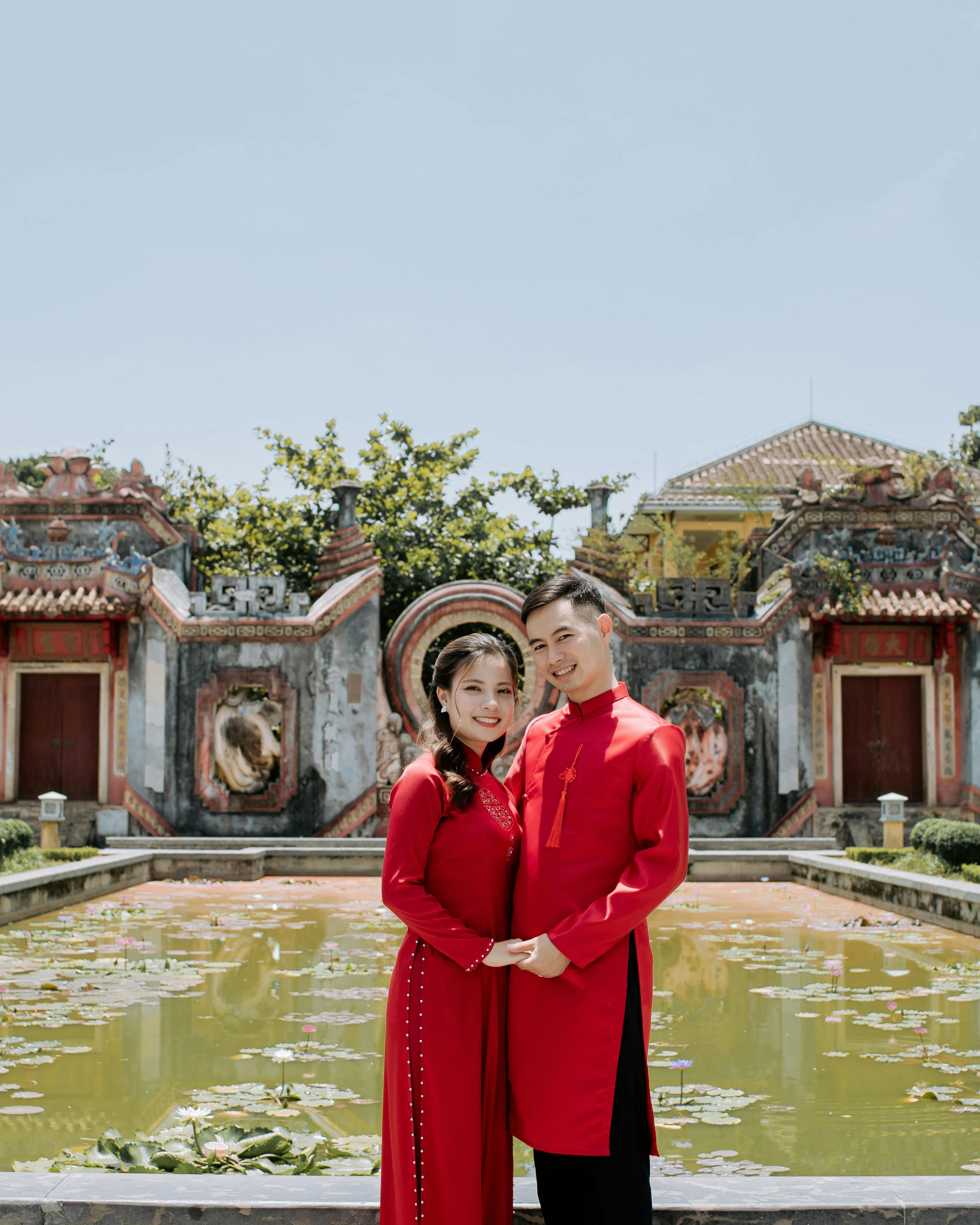 Couple in Red Ao Dai by Lotus Pond