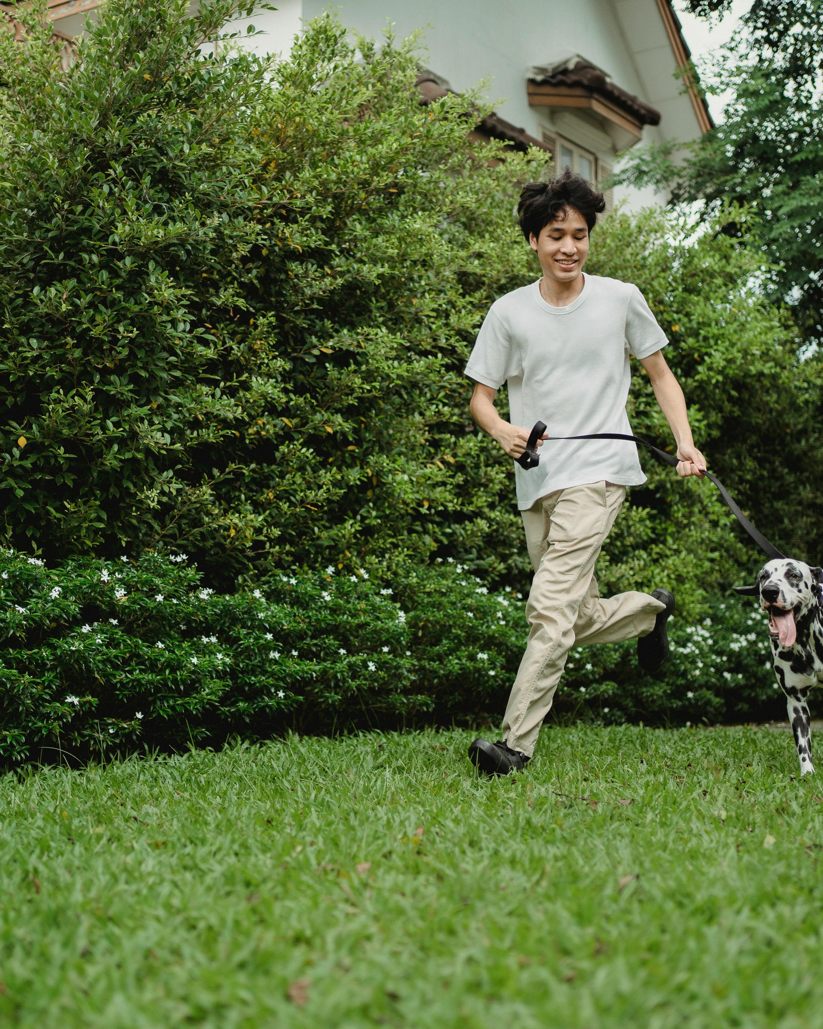 Young Man Running With Dalmatian In Yard