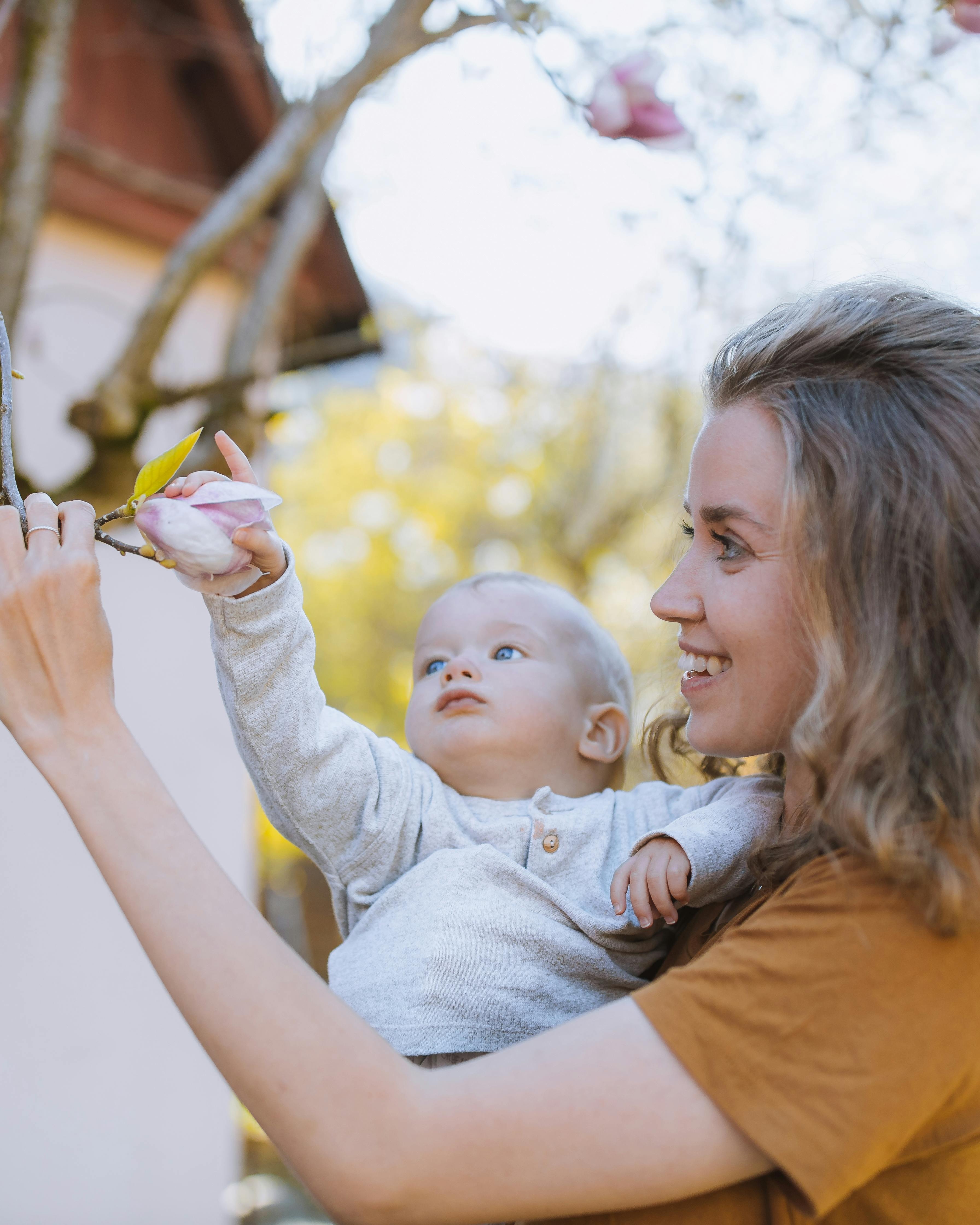 Mother Holding Baby Looking at Magnolia Flower