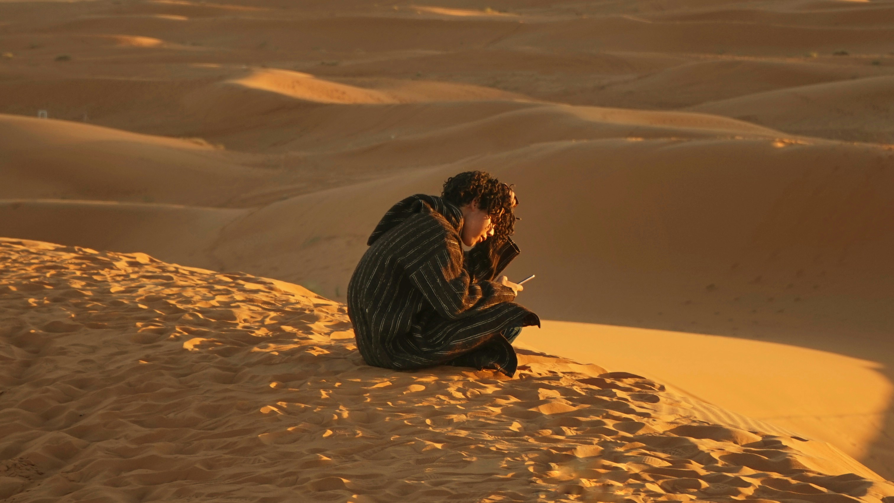 Man Using Phone On Desert Dune