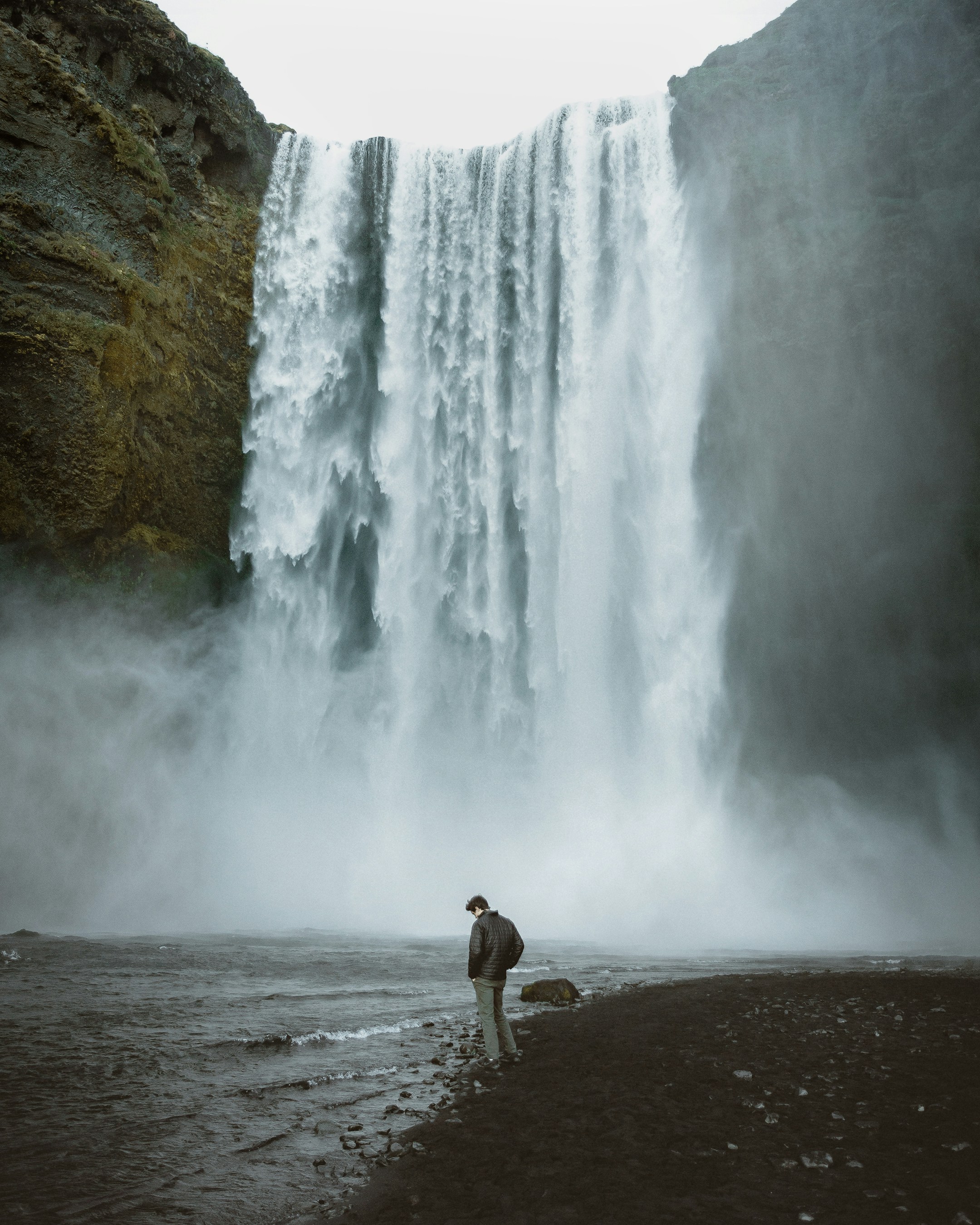Man Standing Before Waterfall