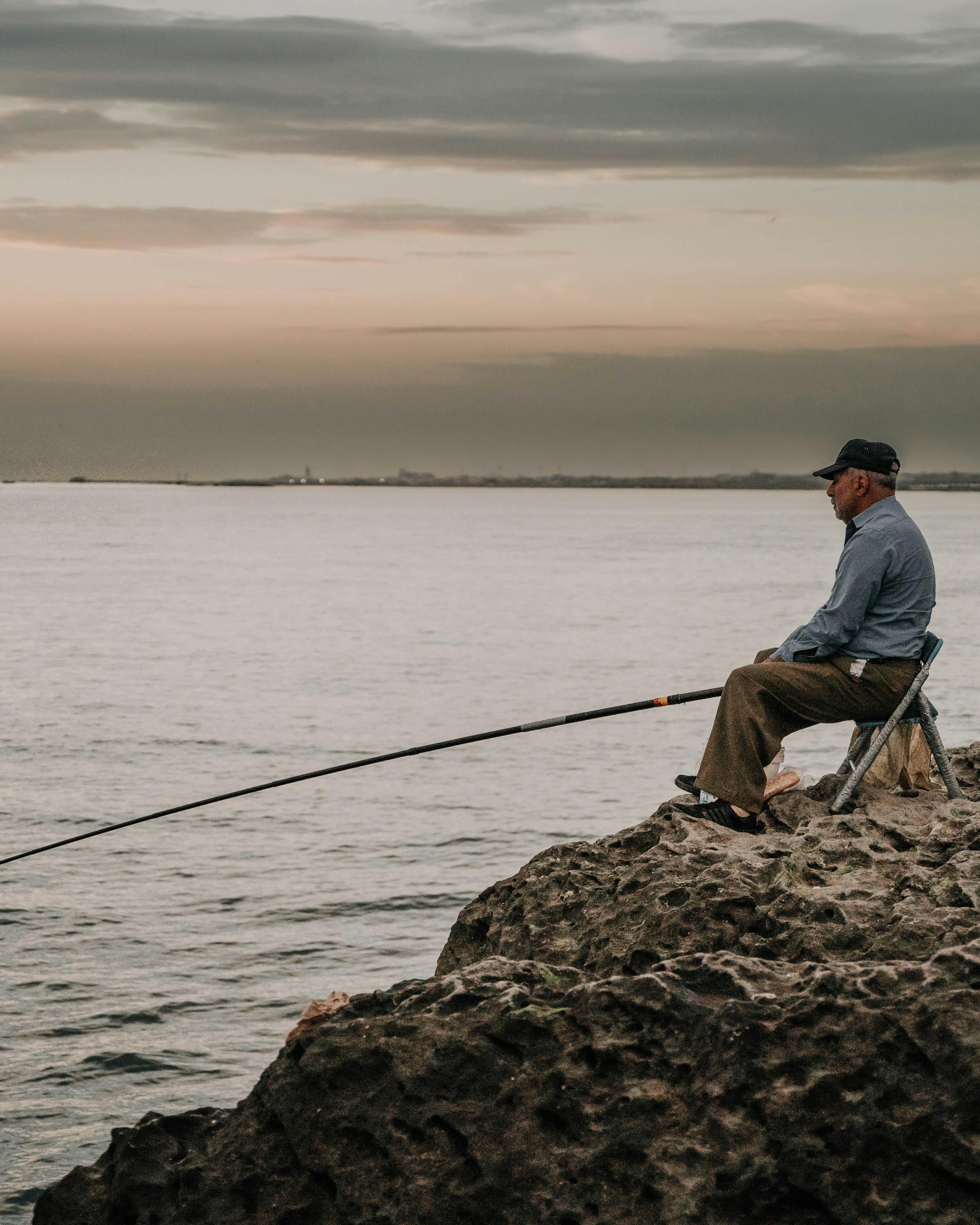 Man Fishing by Calm Sea at Dusk