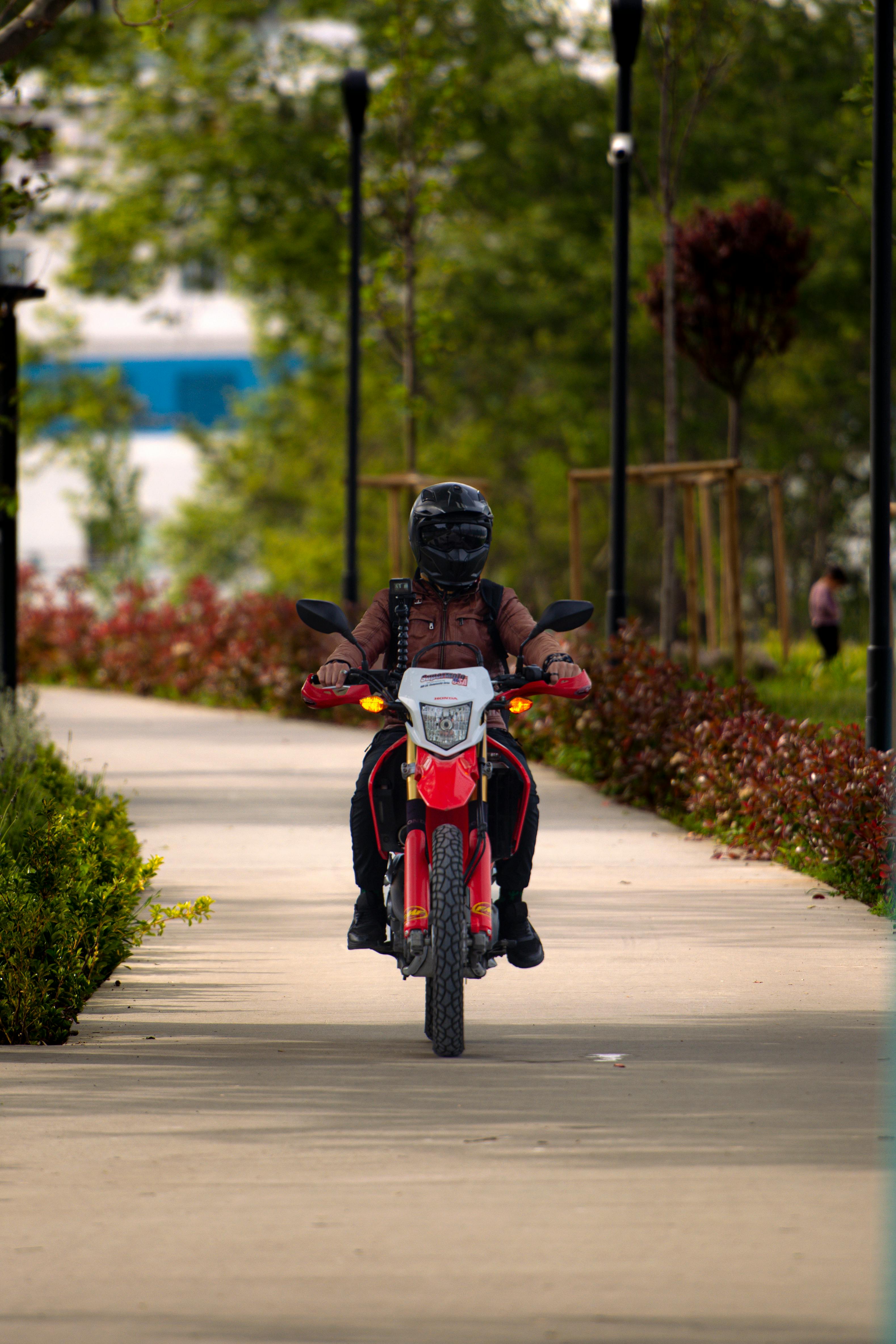 Motorcyclist Riding on Park Path