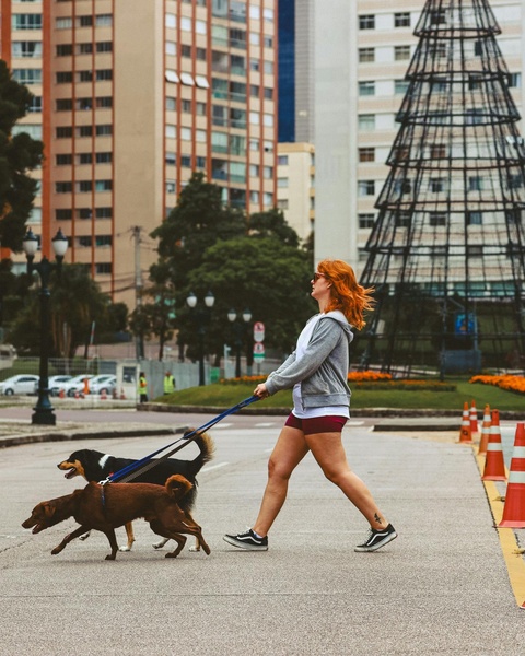 Woman Walking Two Dogs in Urban Plaza