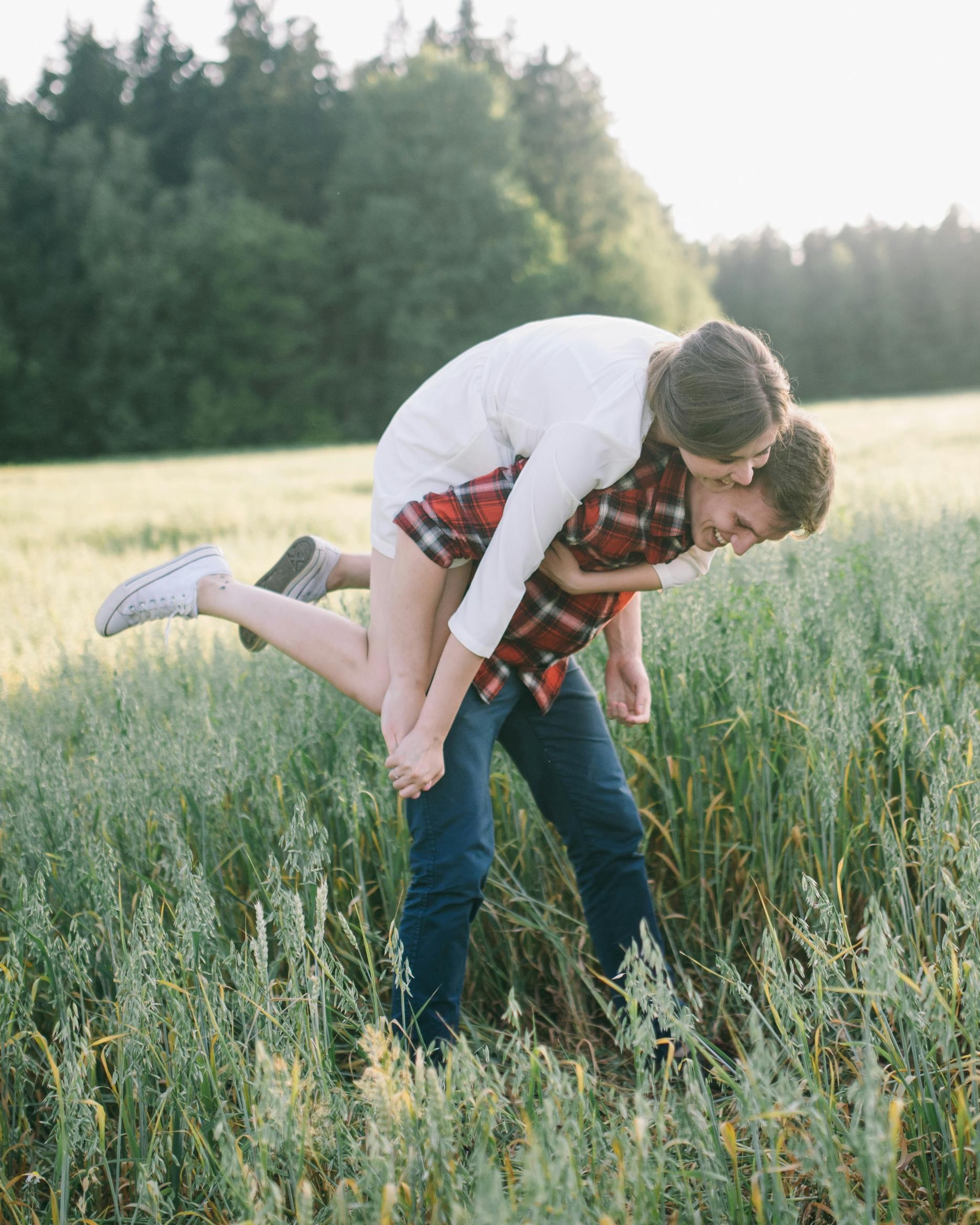 Couple Playing Piggyback in Grass Field