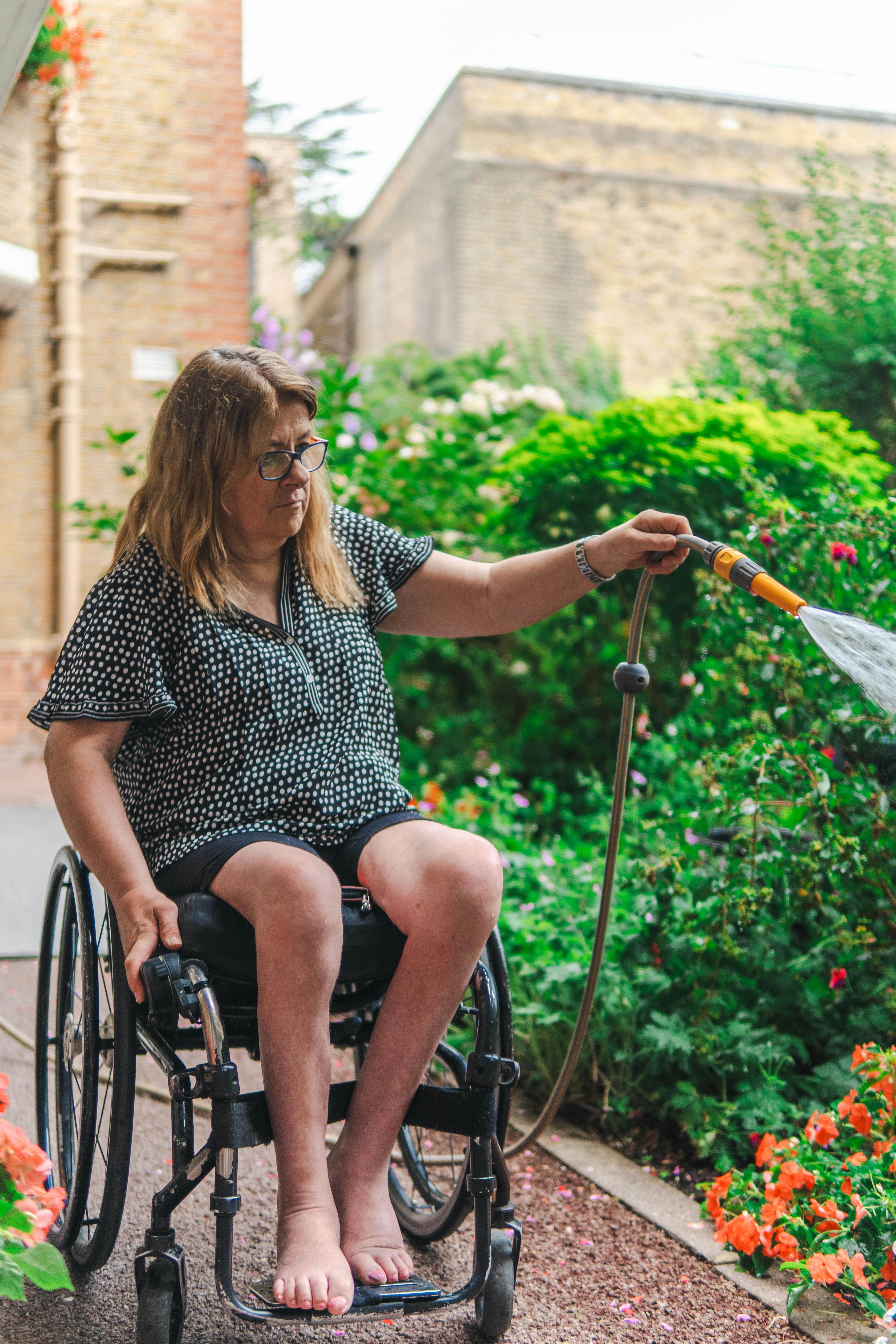 Woman in Wheelchair Watering Garden