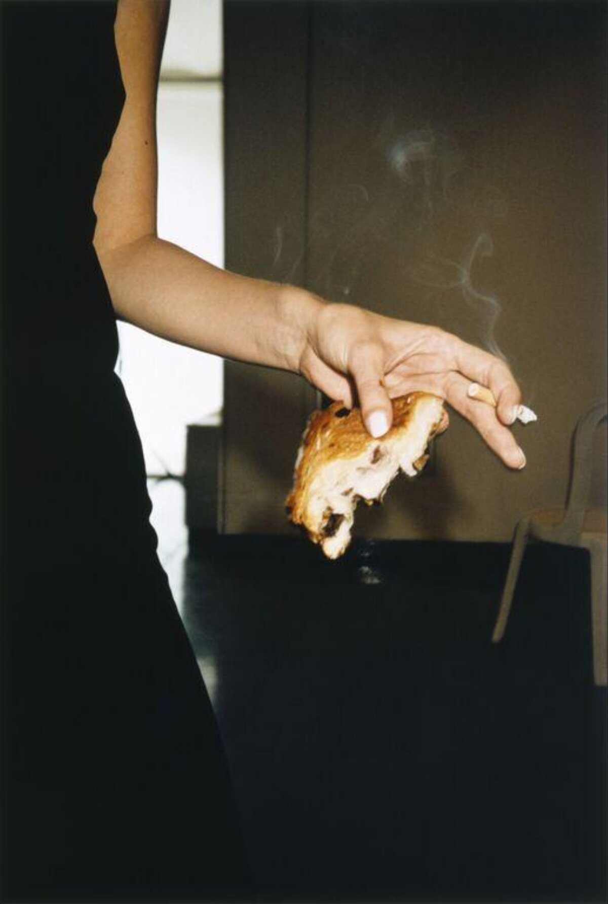 Hand Holding Pastry and Lit Cigarette