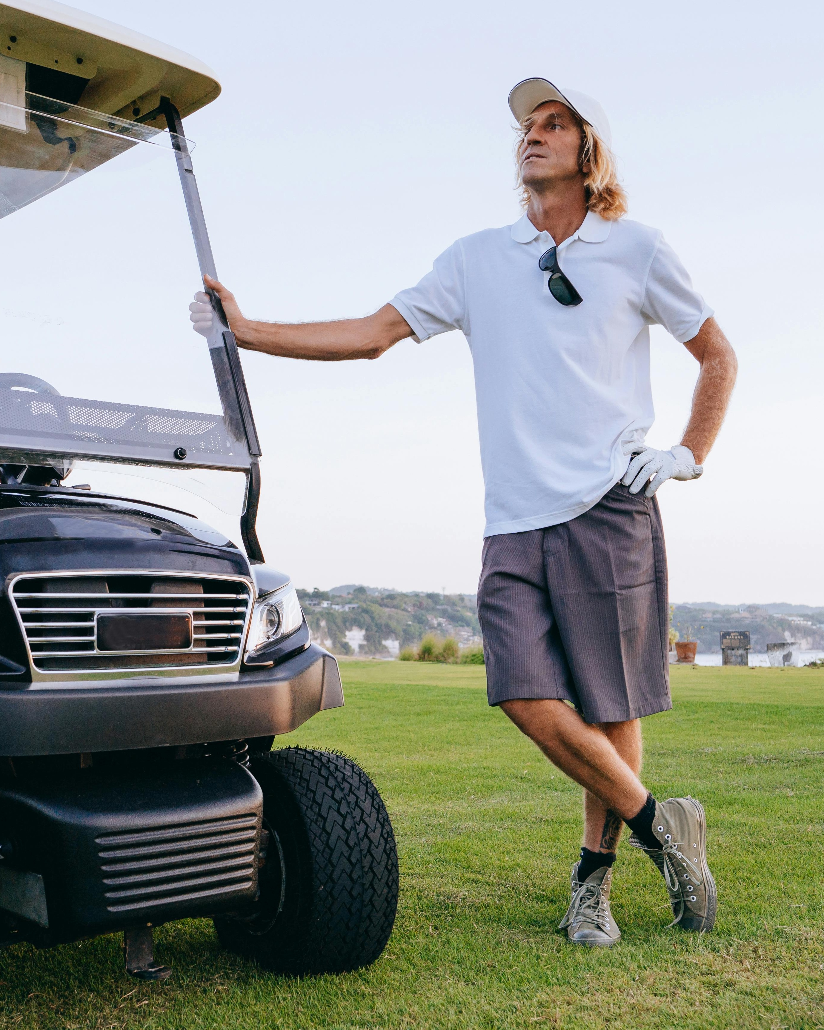 Golfer Standing Beside Golf Cart on Course