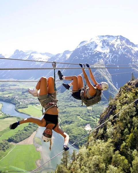 Two People Ziplining Over Mountain Valley