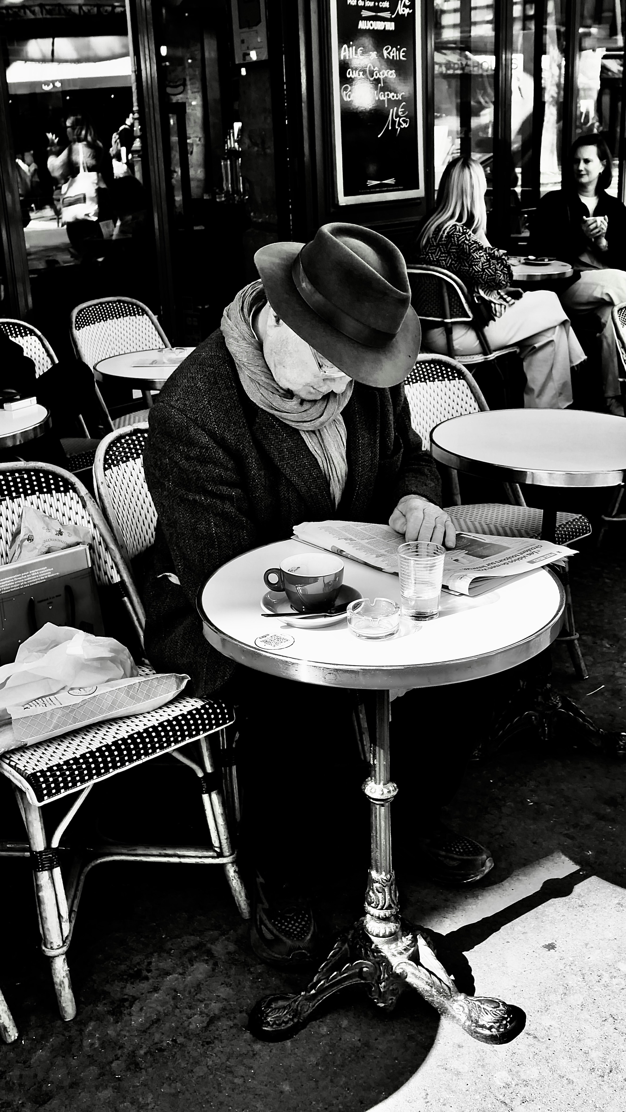 Man Reading Newspaper at Outdoor Cafe