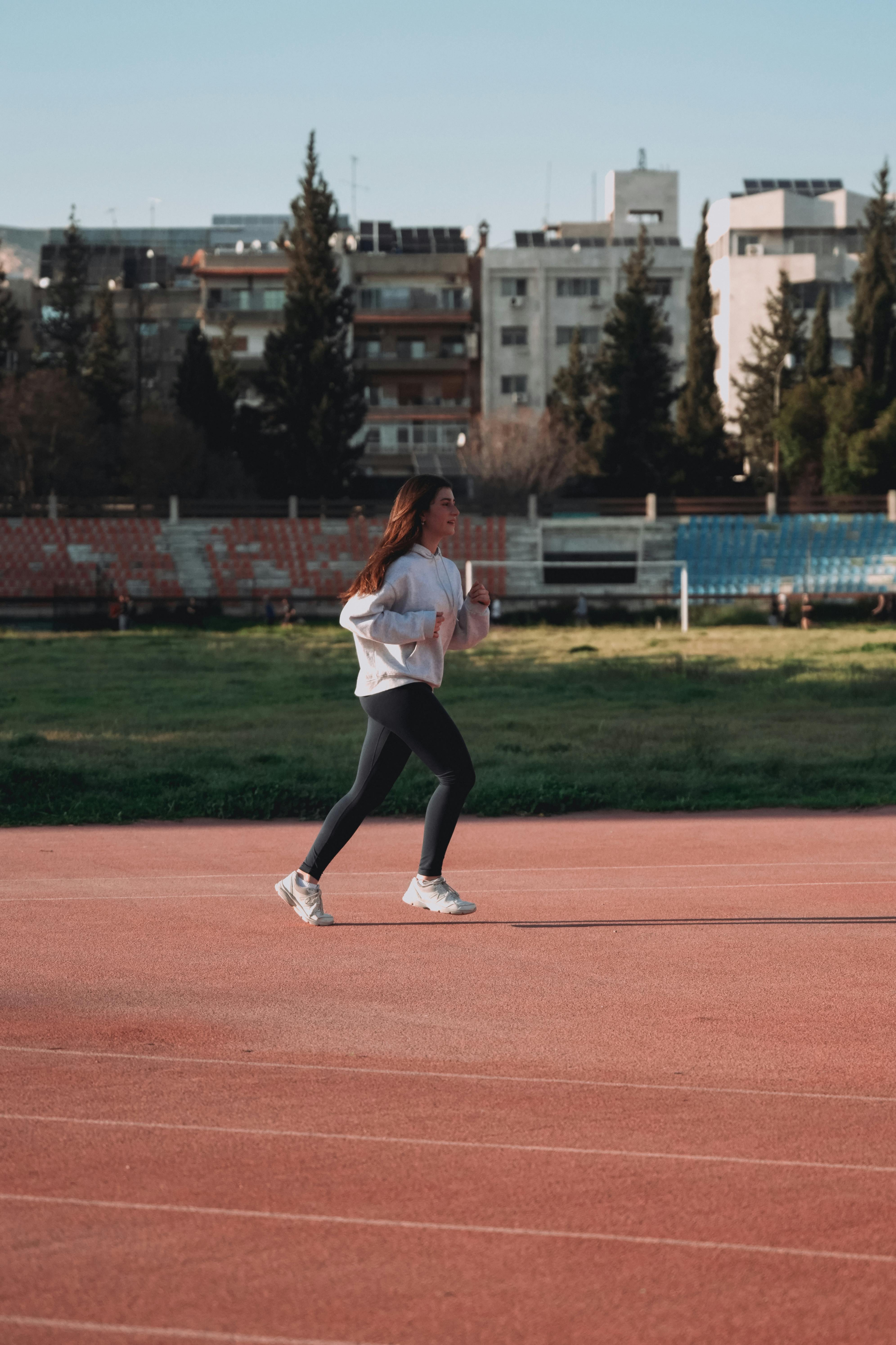 Woman Jogging on Outdoor Stadium Track