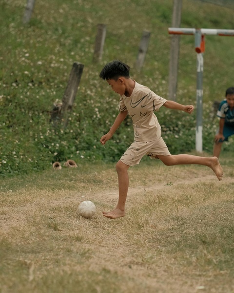 Barefoot Boy Playing Soccer Outdoors