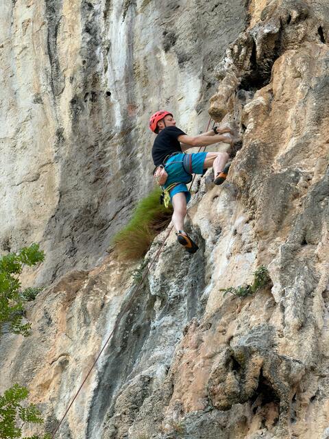Man Rock Climbing on Steep Cliff