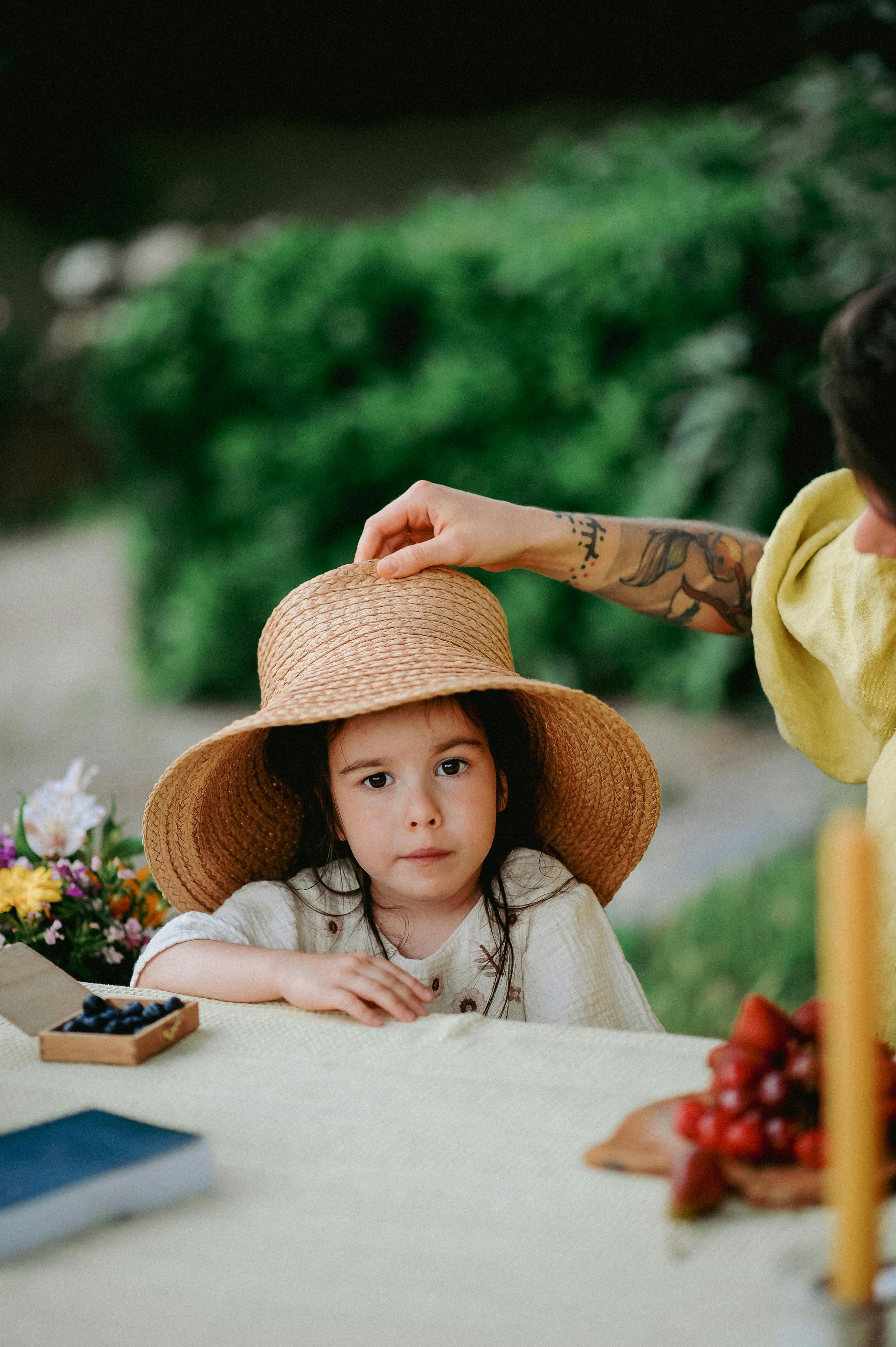 Adjusting Straw Hat on Little Girl at Picnic