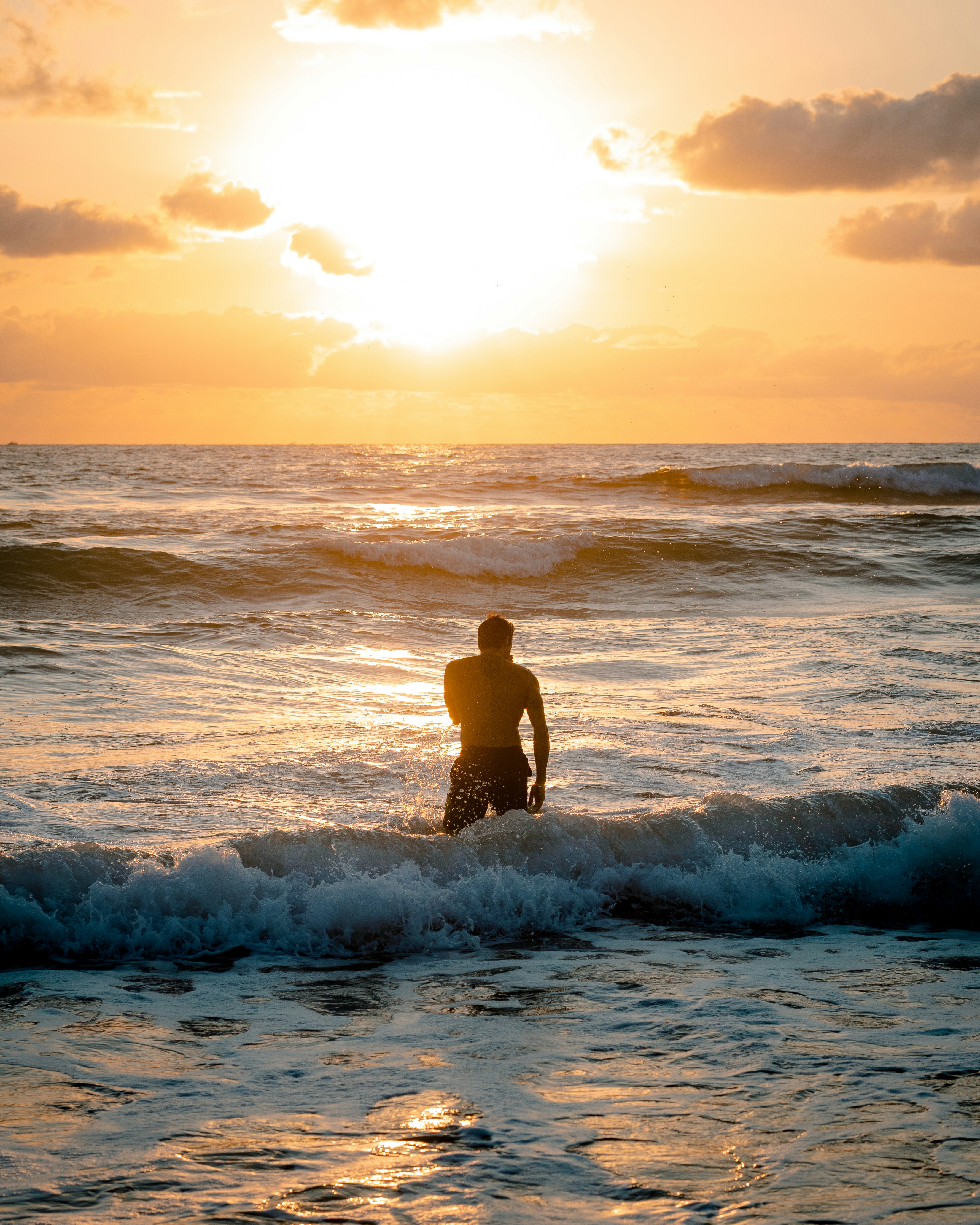 Man Standing In Sea At Sunset