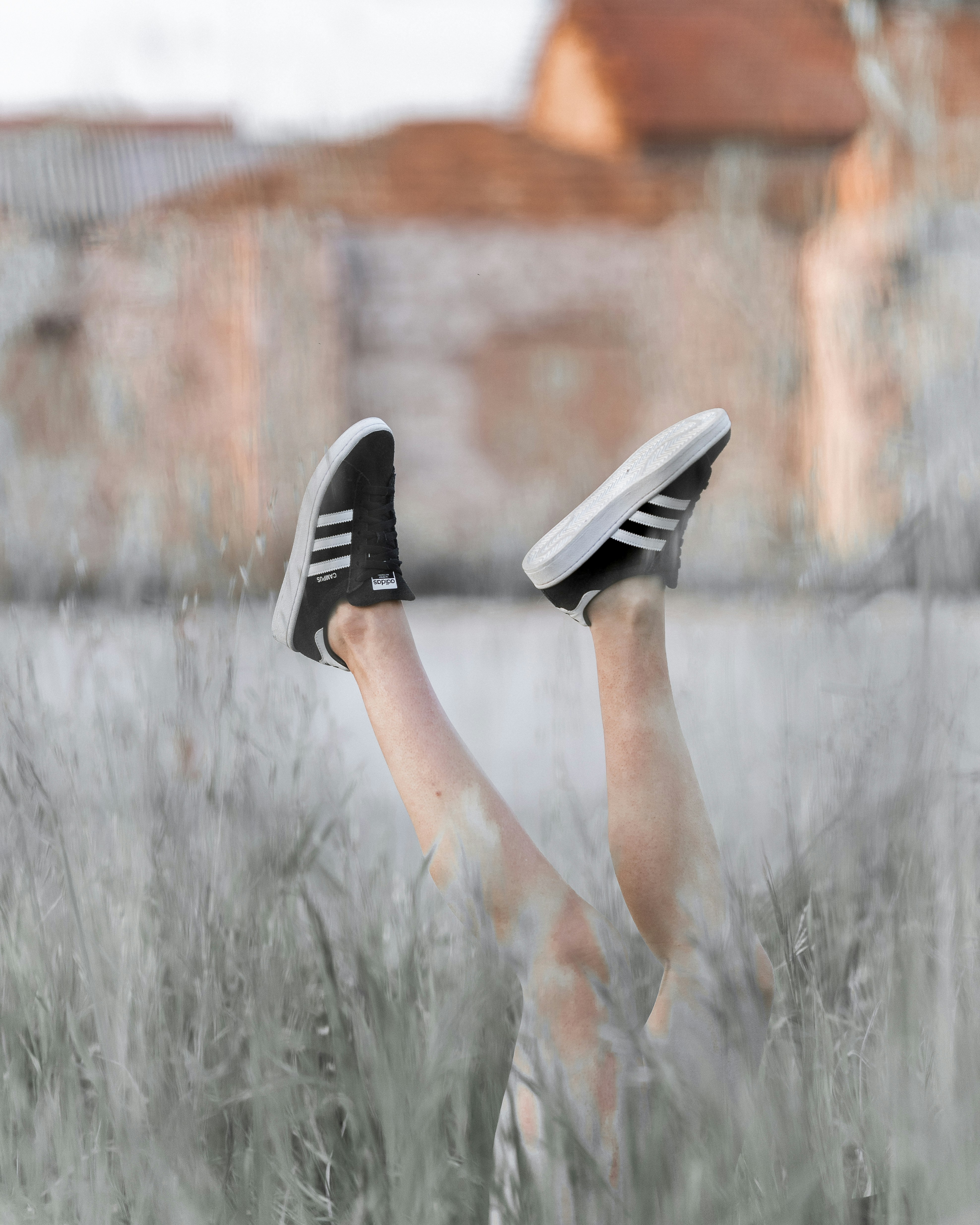 Legs in Adidas Sneakers Sticking Out of Tall Grass