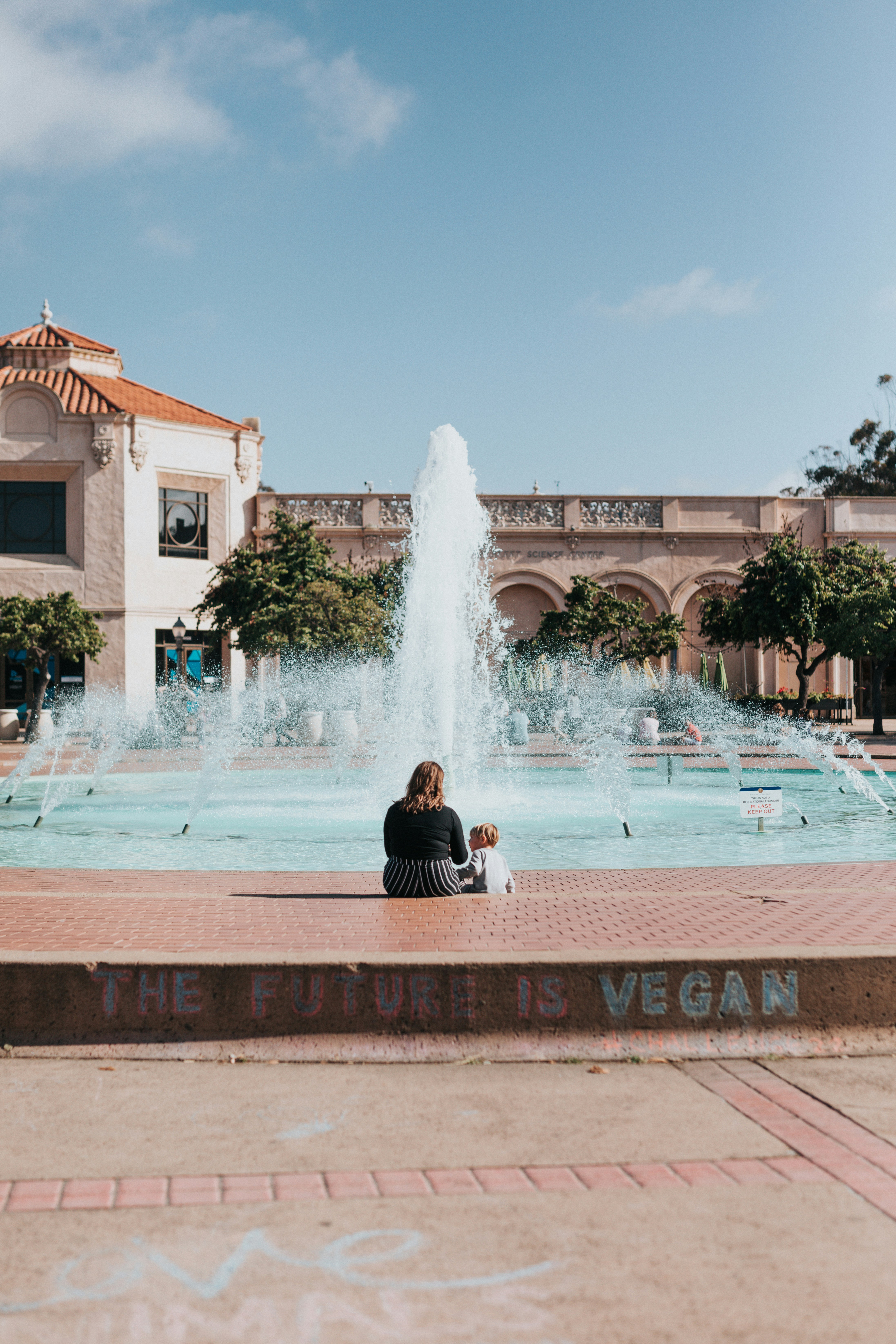 Woman And Child By Fountain With Vegan Graffiti