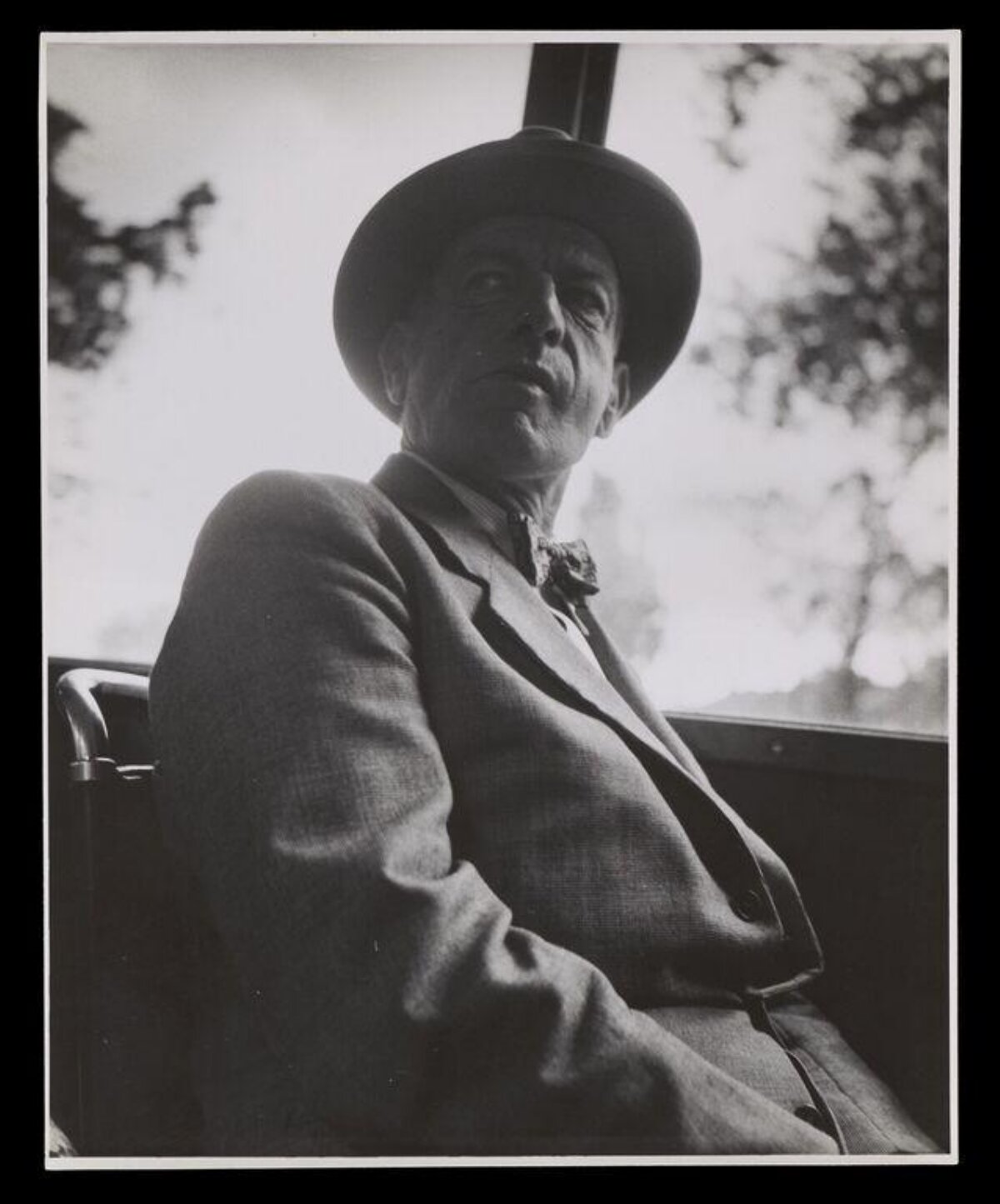 Man in Hat Seated in Open Car