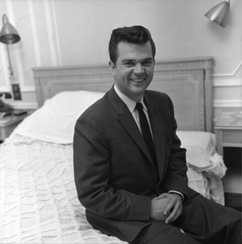 Smiling Man in Suit Sitting on Bed