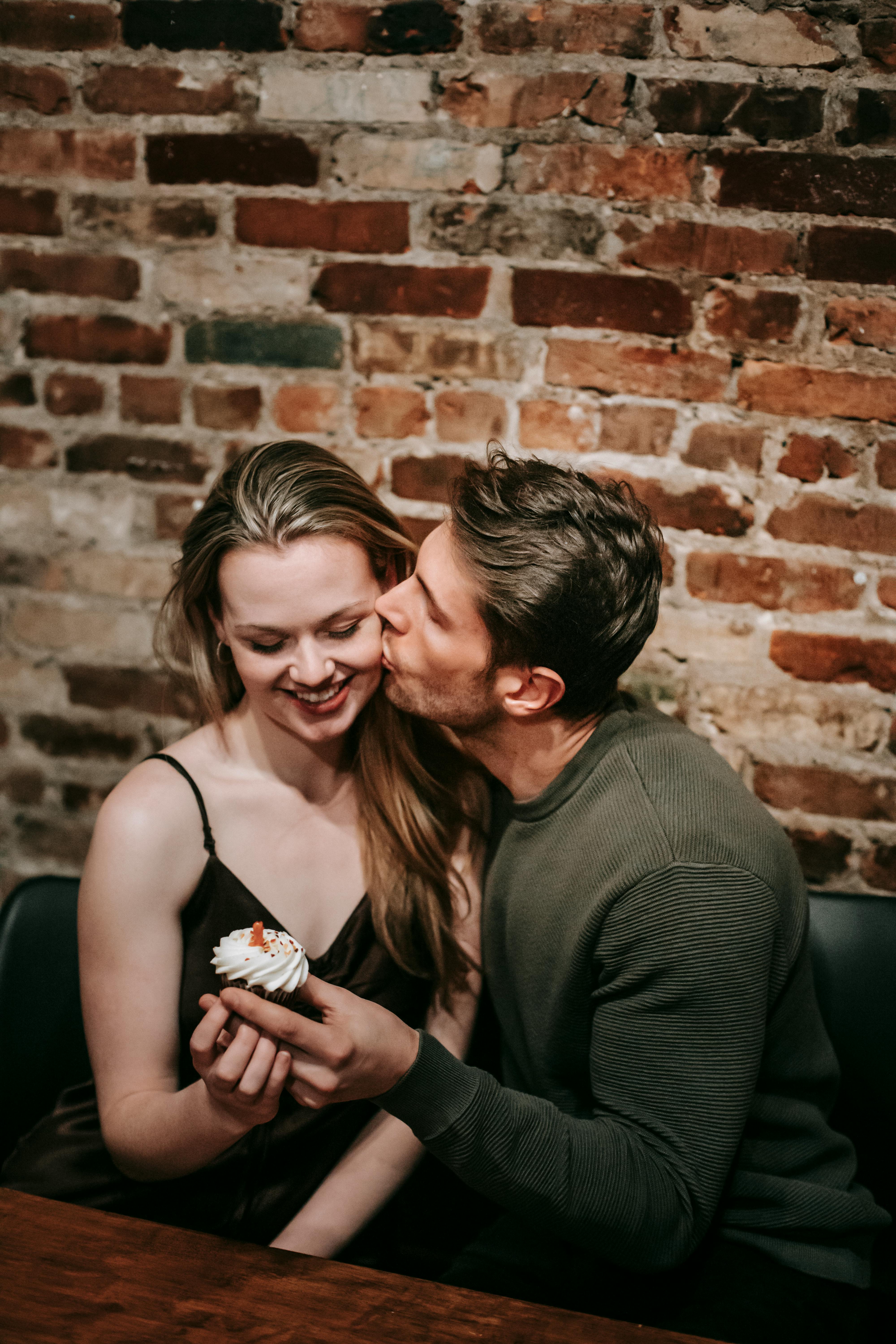 Man Kisses Woman While Sharing Cupcake